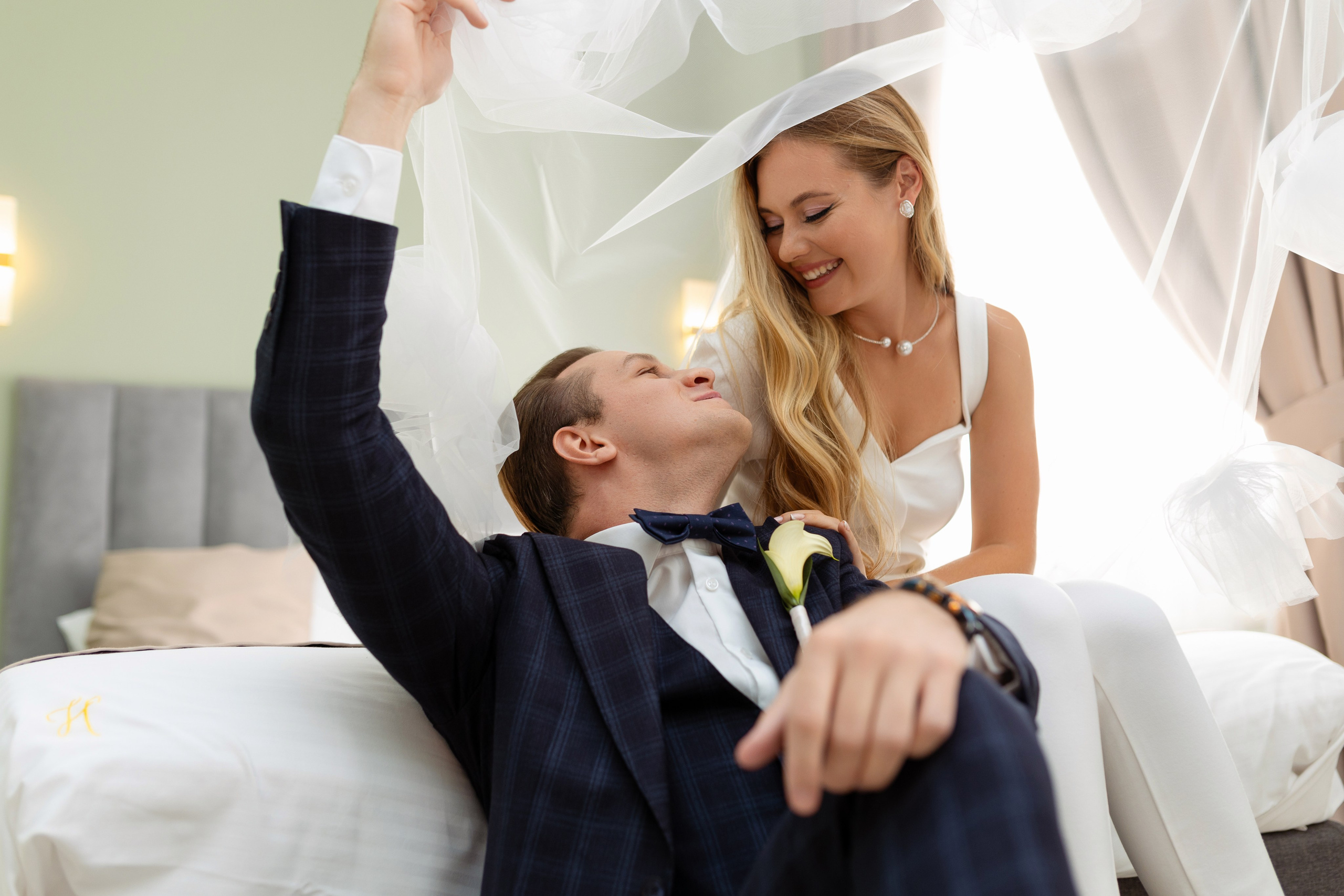 Невеста сидит на кровати у ее ног сидит жених.