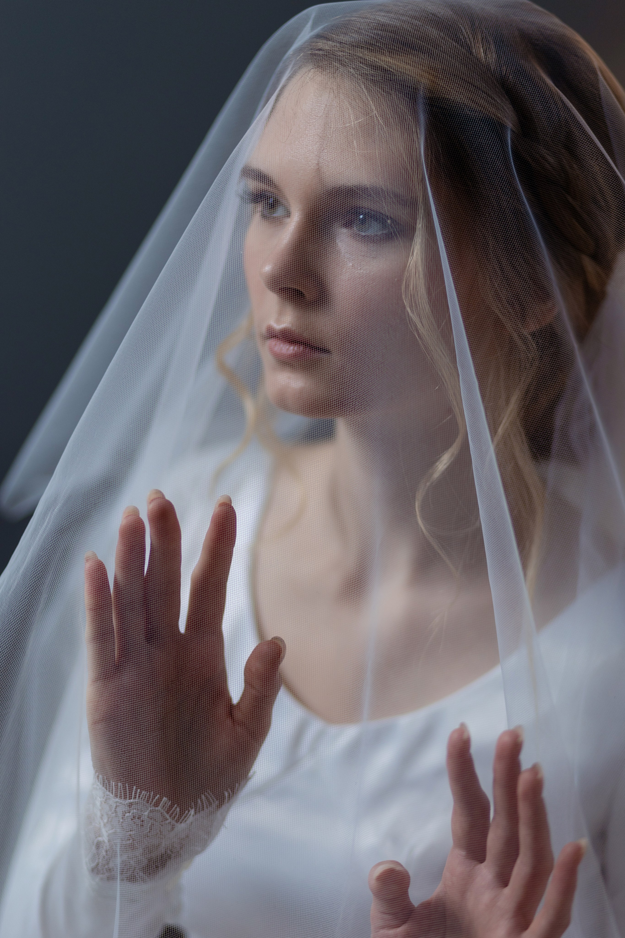 Невеста покрыта свадебной вуалью в полупрофиль.