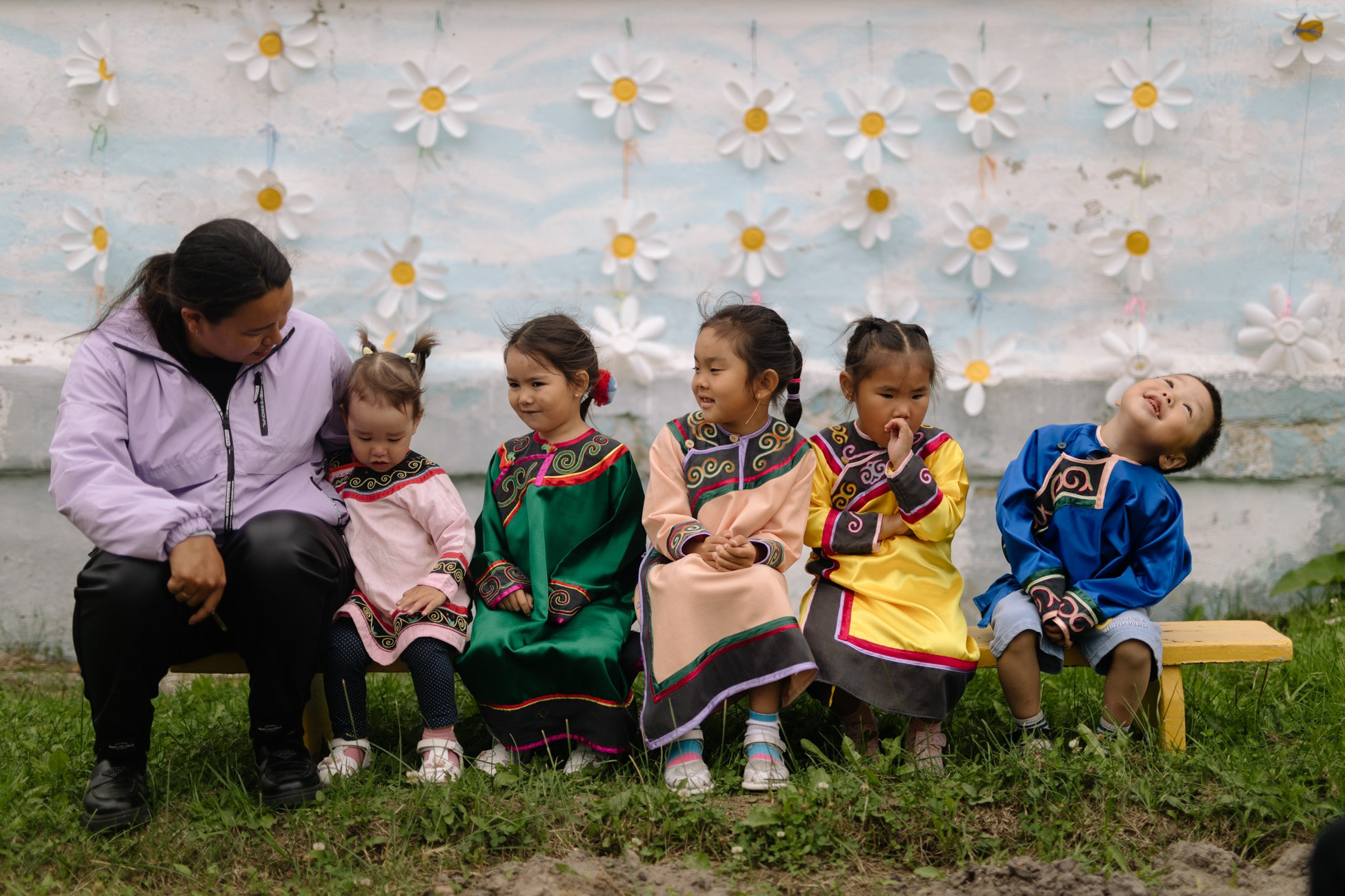 Junior students of the Nekrasovka Boarding School named after P.G. Chaika in national costumes are sitting on a bench in the school yard.