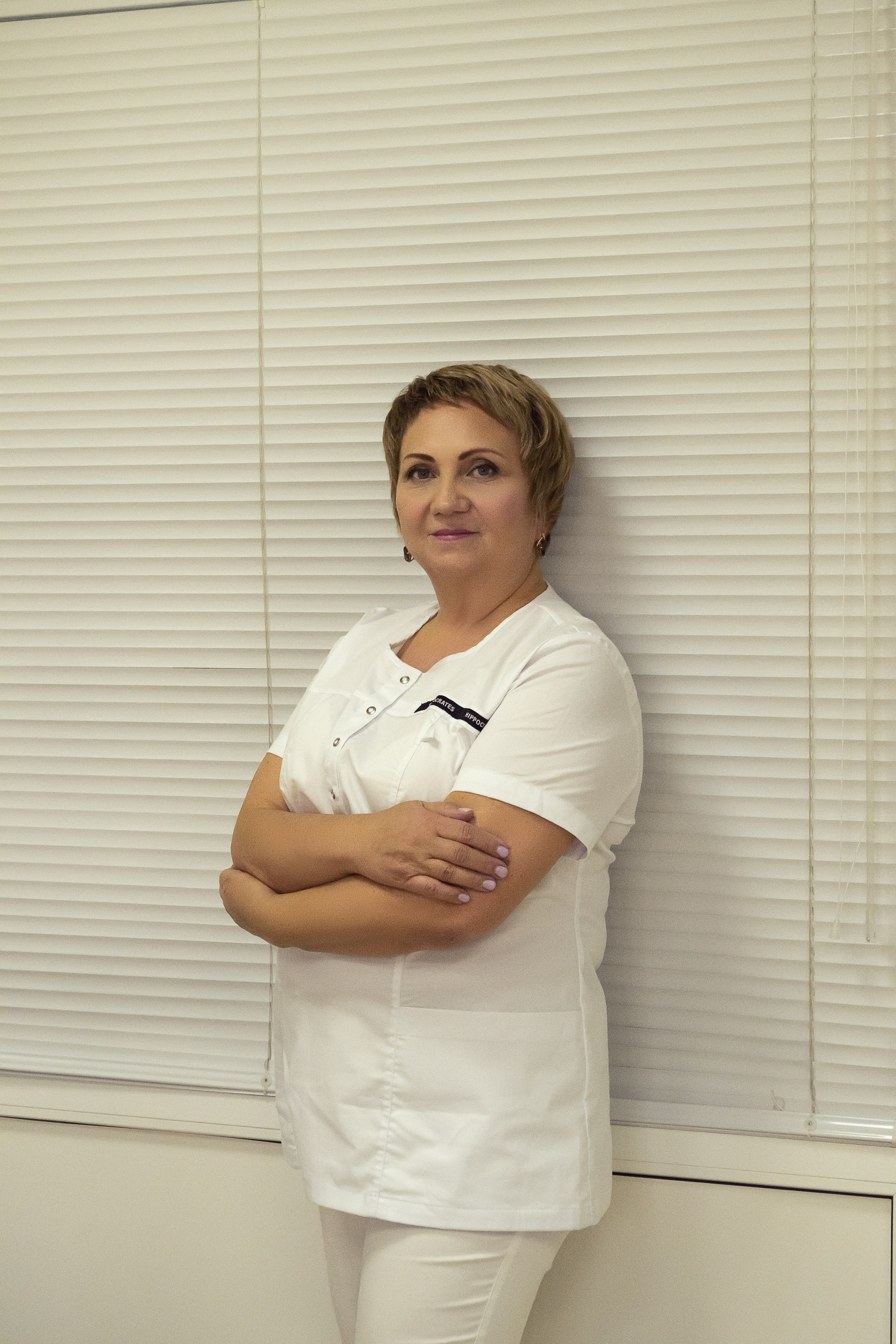 Портрет женщины-врача в кабинете на белом фоне.