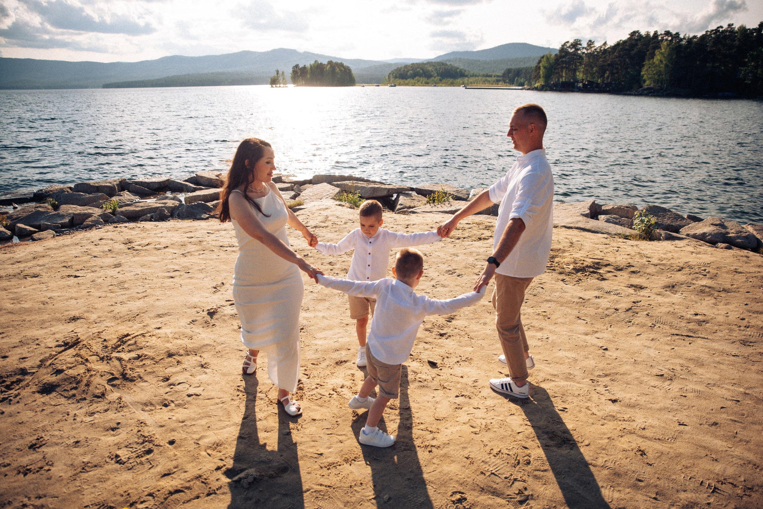 Семейная прогулка летом на берегу озера по пляжу