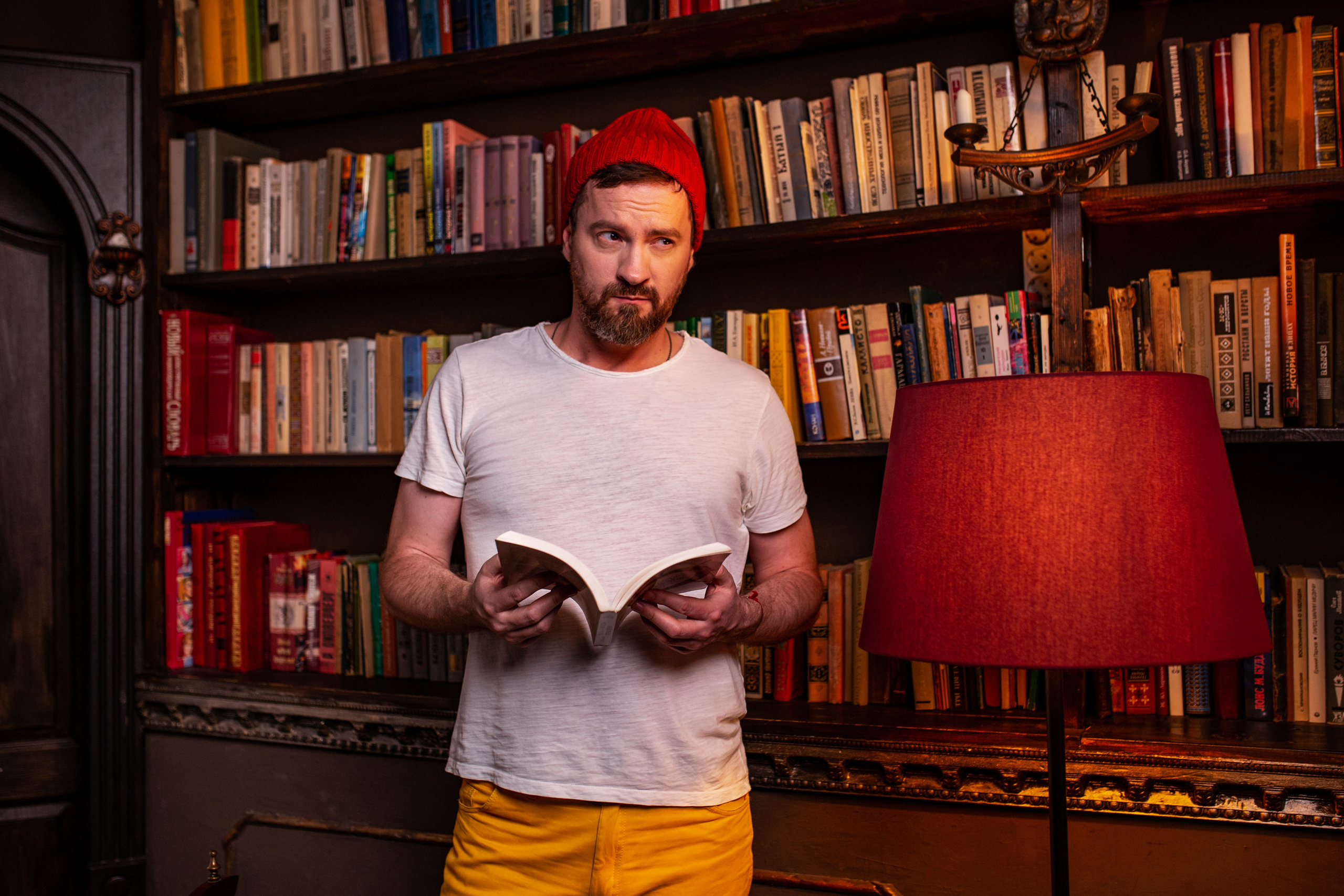 Парень читает в библиотеке.