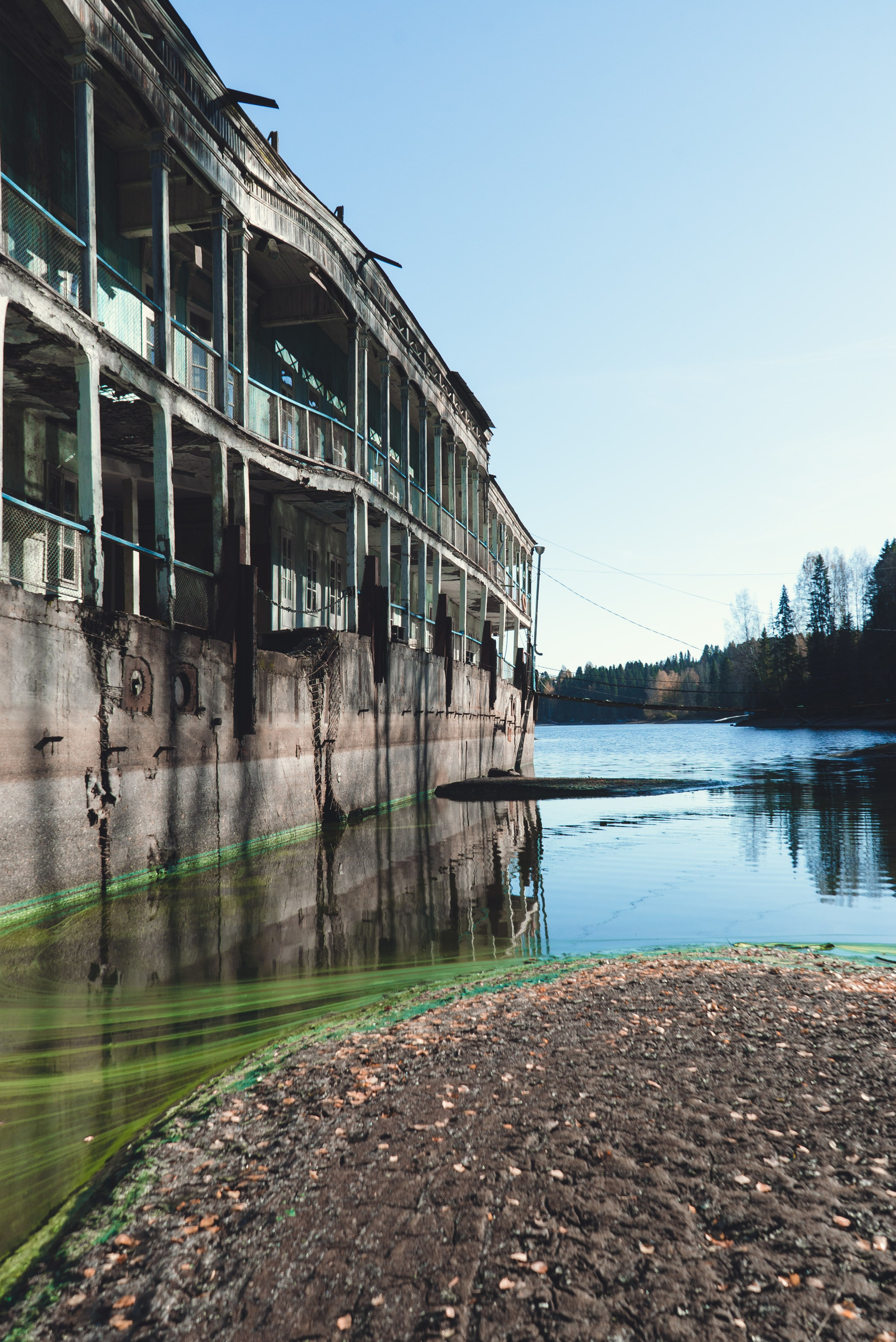 Заброшенное здание, виднеющееся на старинном берегу речной пароход, стоит на водоеме среди густого леса. Его фасад украшен колоннами и балконами, однако здание выглядит ветхим и запущенным: краска облупилась, металл покрыт ржавчиной. Вокруг голые деревья и хвойные леса, что создает ощущение уединенности и застенчивости.