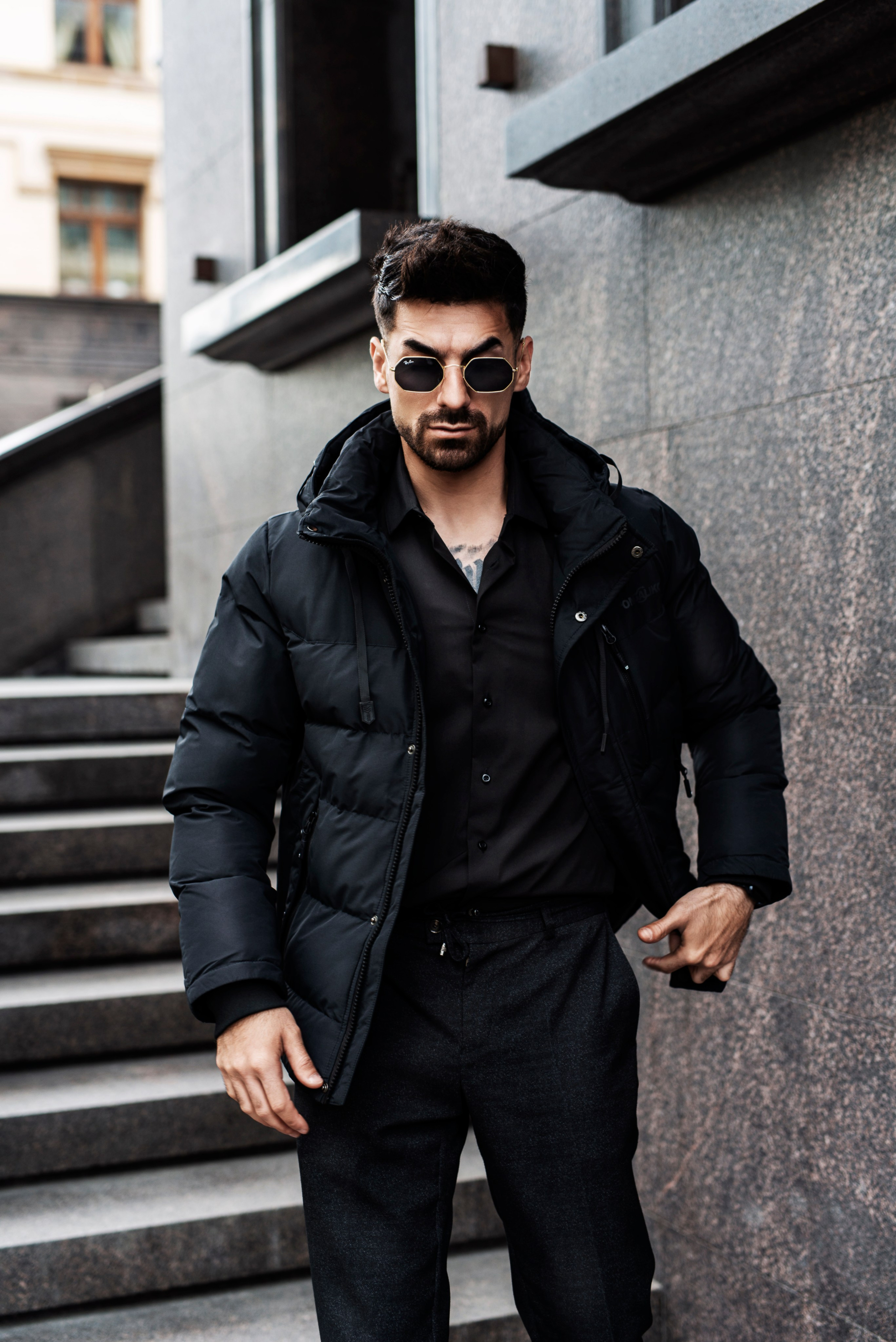 Стильно одетый мужчина позирует на фоне городского пейзажа во время фотосессии