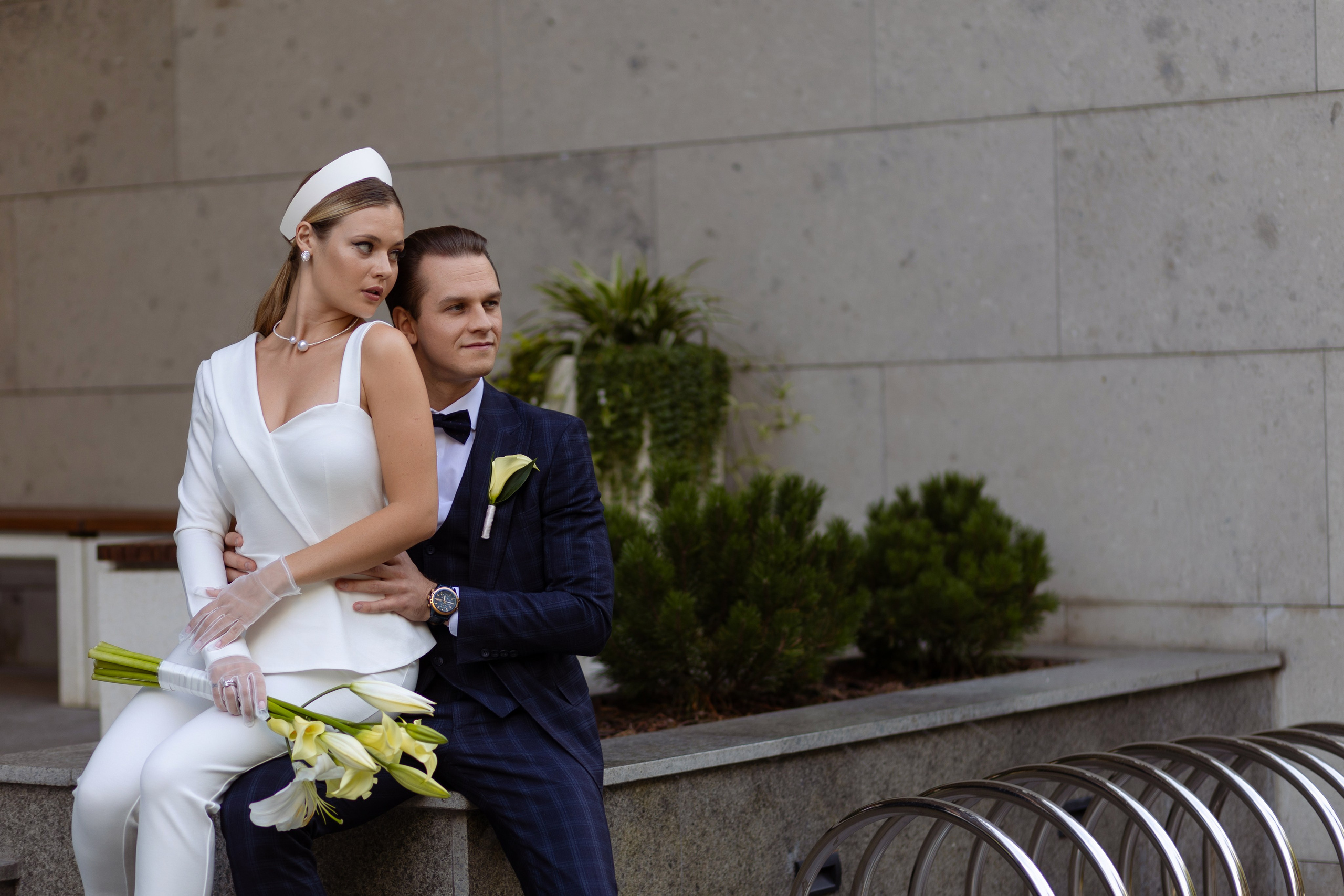 Молодые сидят на парапете и смотрят в сторону.