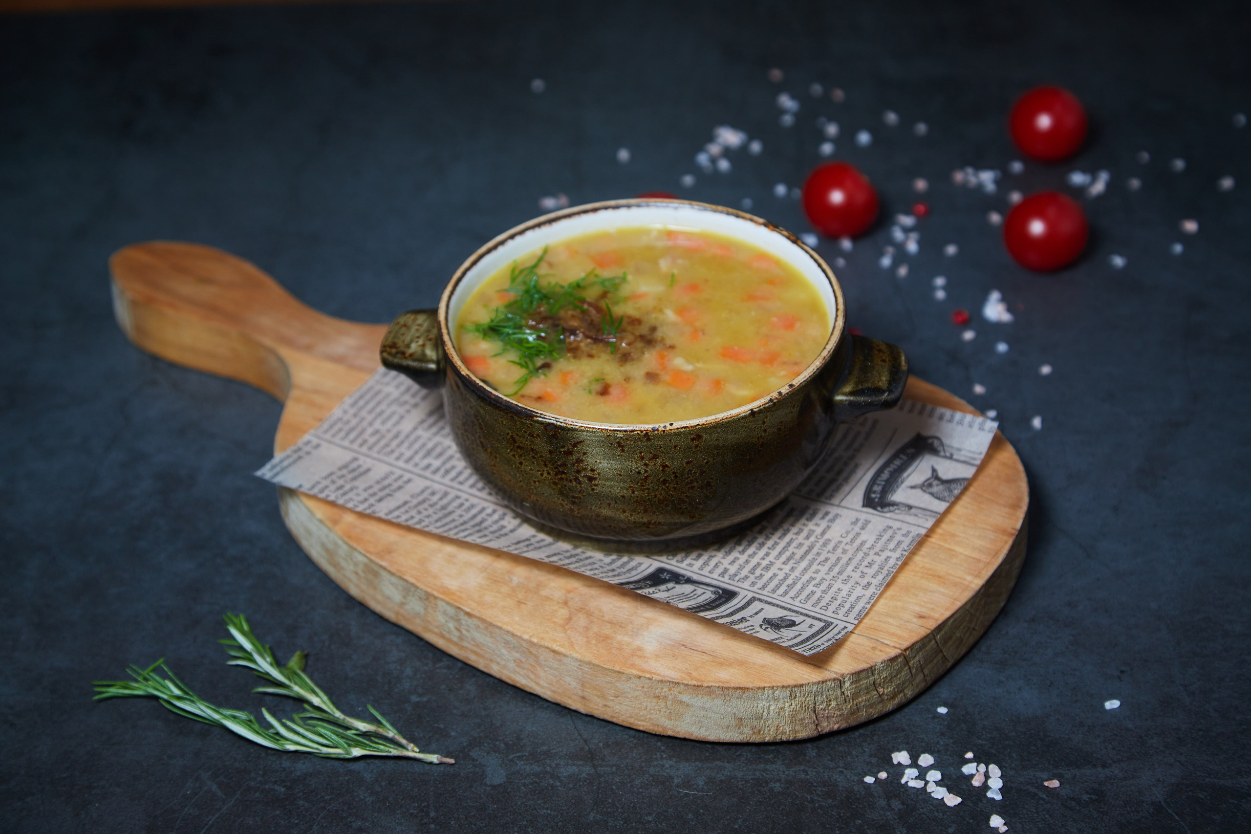 Суп в пиале с ложкой и зеленью на подставке.