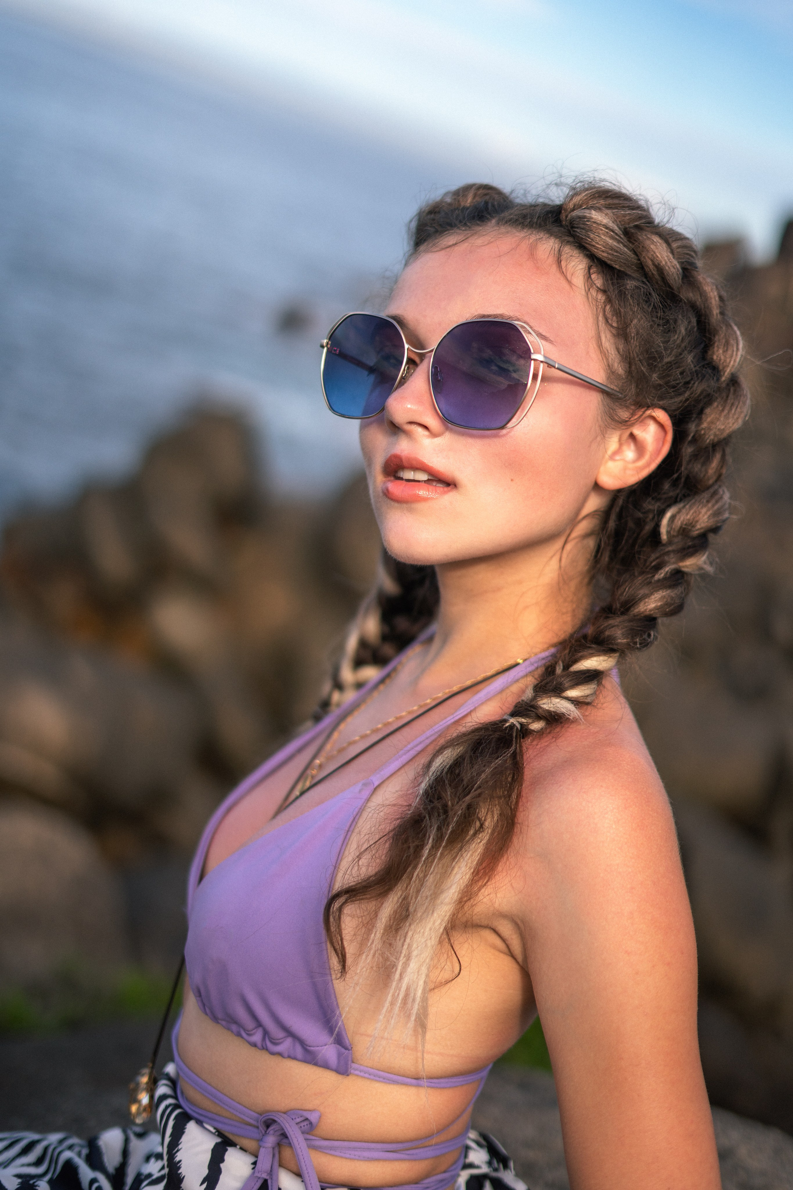 a girl in a purple swimsuit enjoying a sunny day on the rocks by the ocean