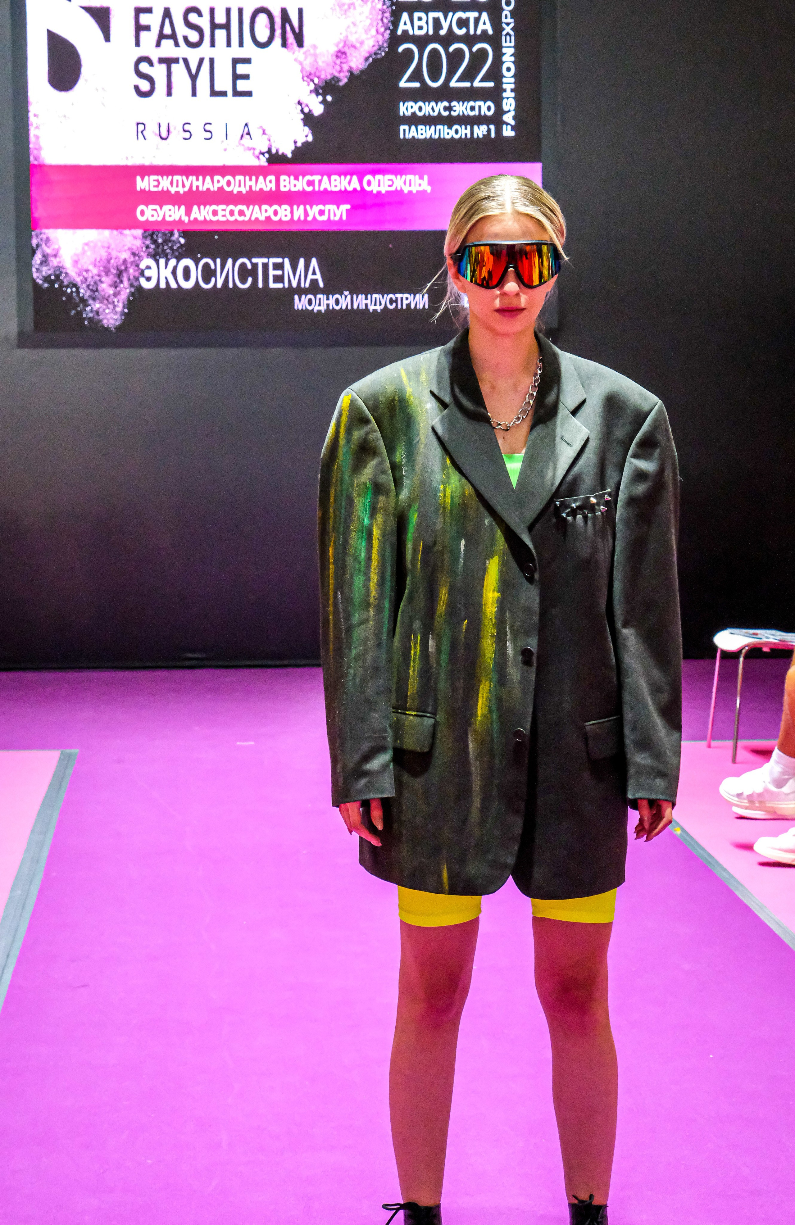  "Модели в ярких нарядах проходят по подиуму во время показа мод, освещенные яркими софитами и окруженные восторженными зрителями."