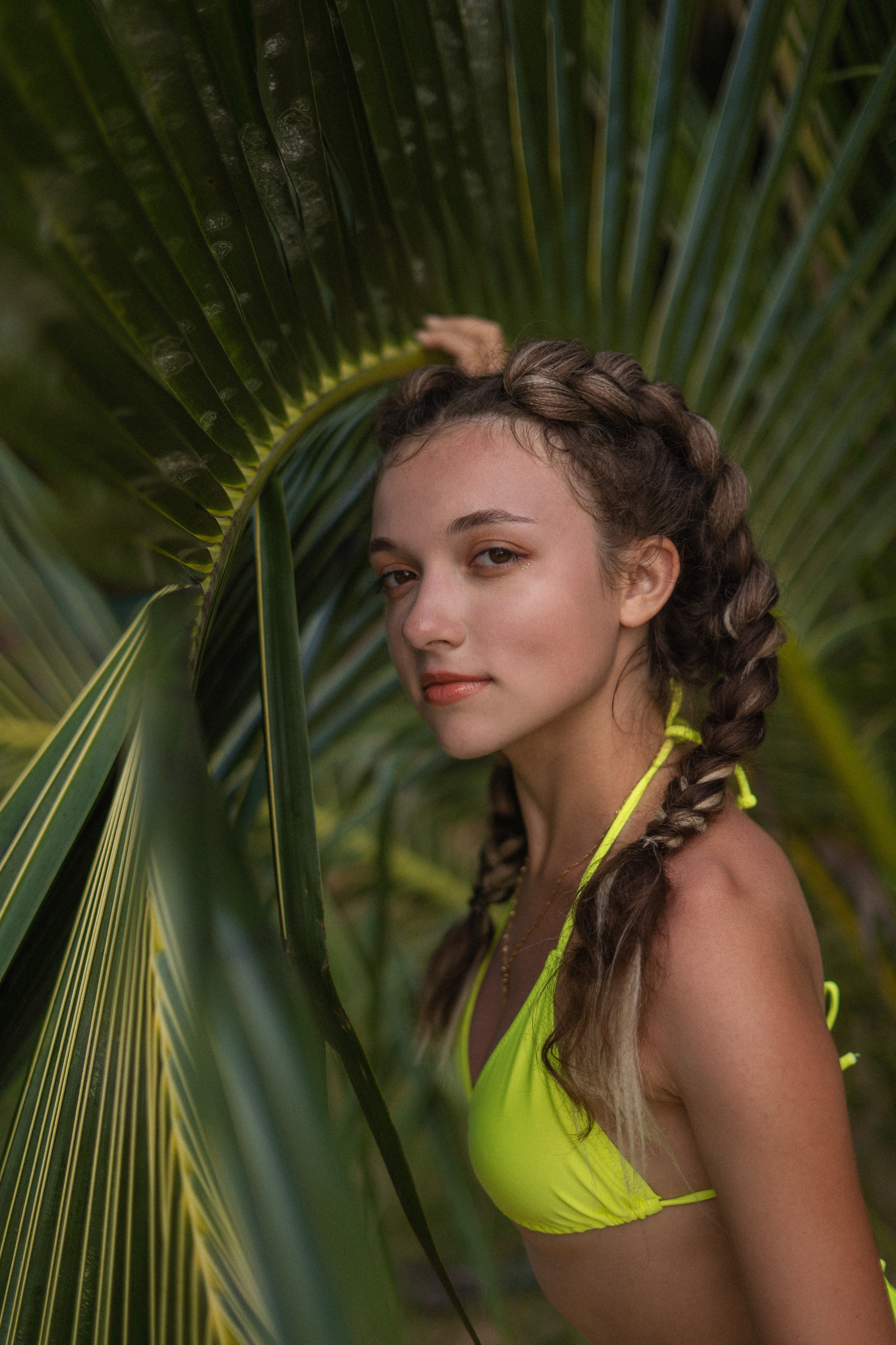 a girl with braids in a yellow swimsuit posing by the ocean