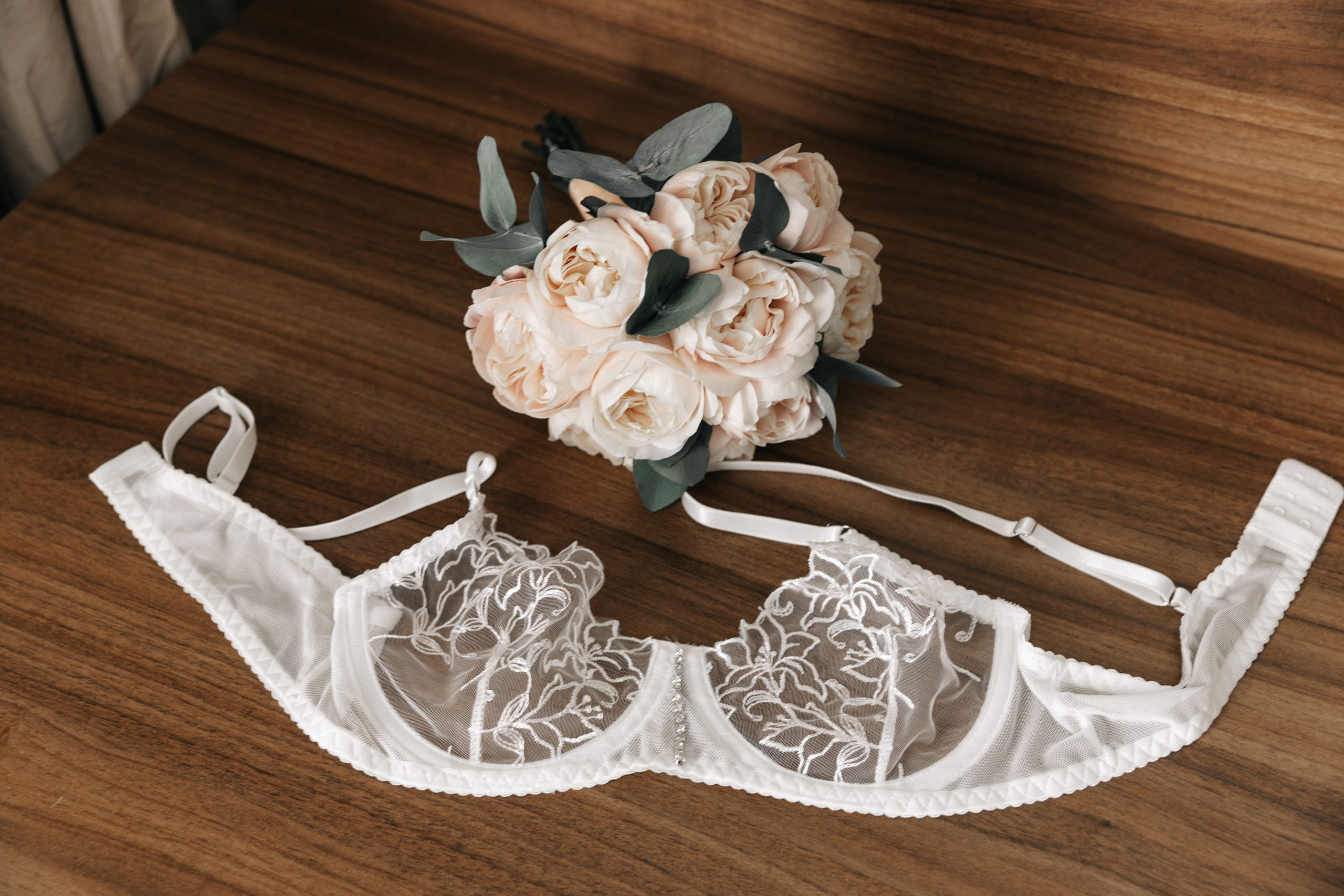 бюстгальтер и букет невесты красиво лежат на столе 