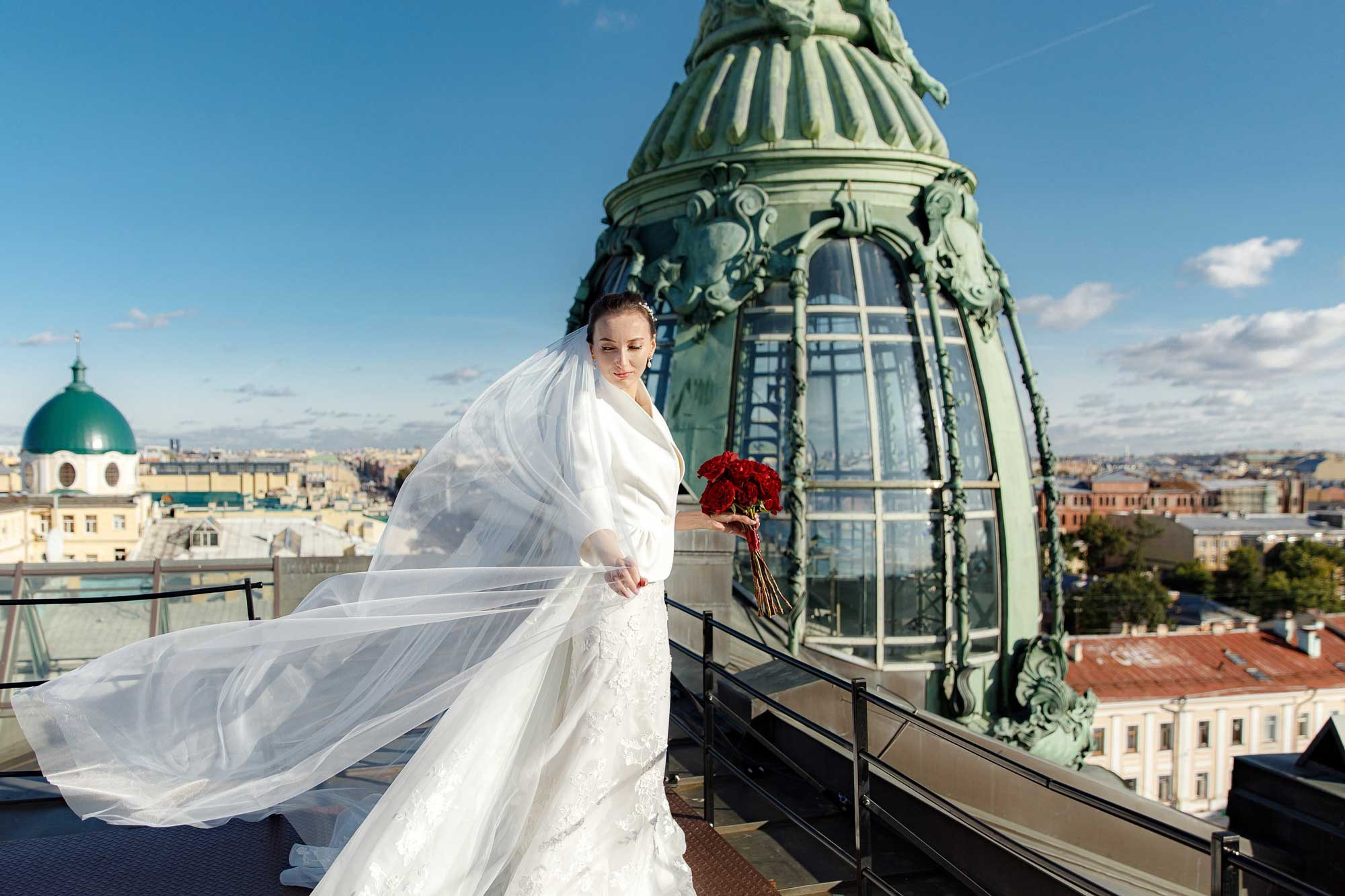 Невеста с фатой и букетом красных роз на крыше Дома Зингер
