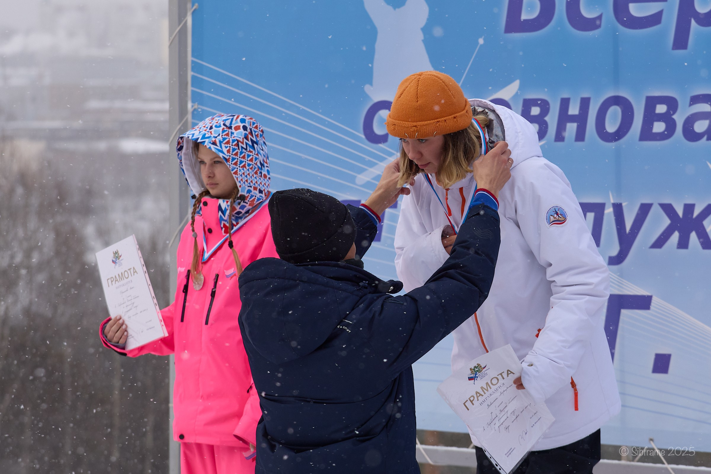 Артём Валентеев вешает медаль на шею спорстменке.