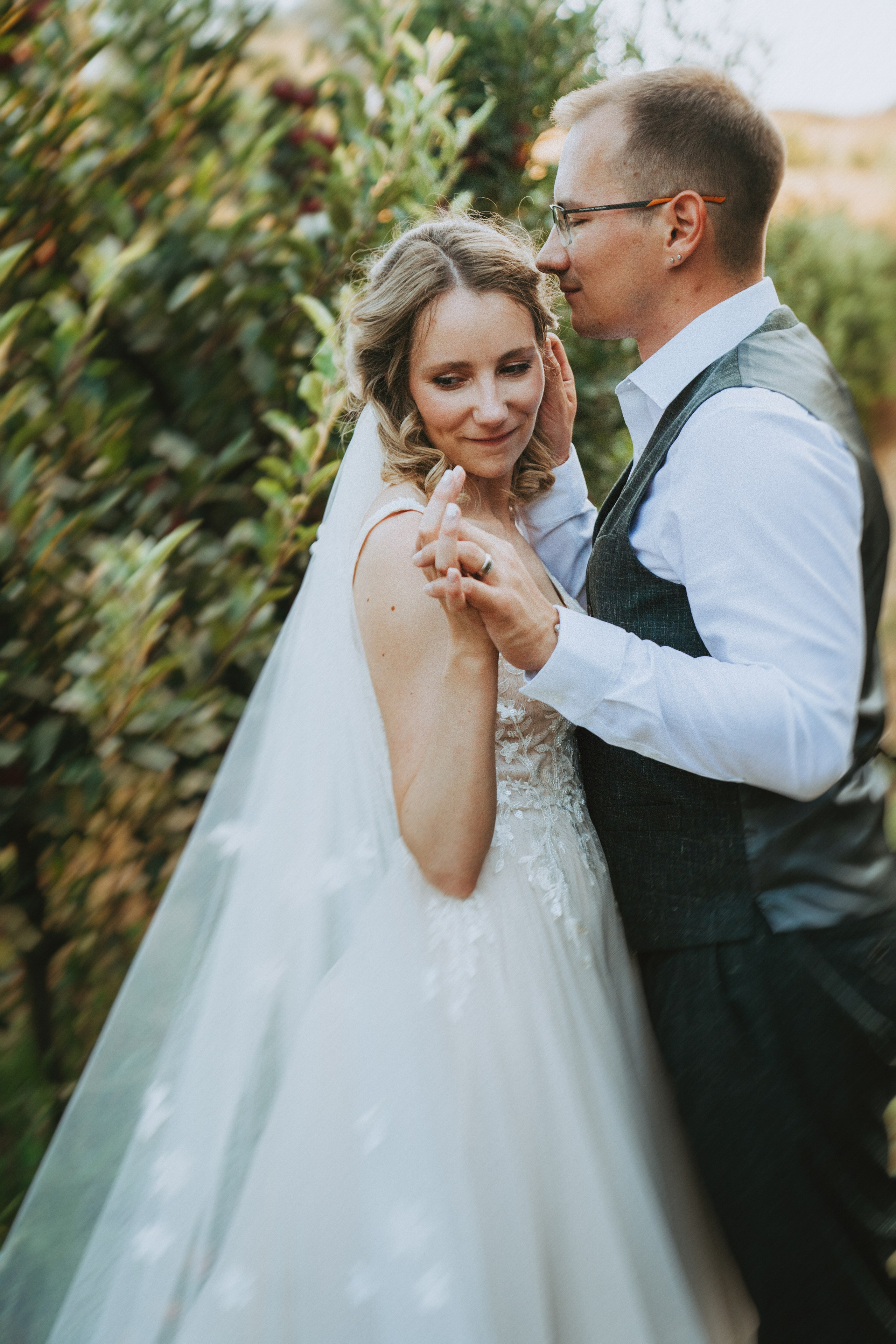 Жених и невеста обнимаются среди яблоневого сада, вокруг созревшие яблоки.