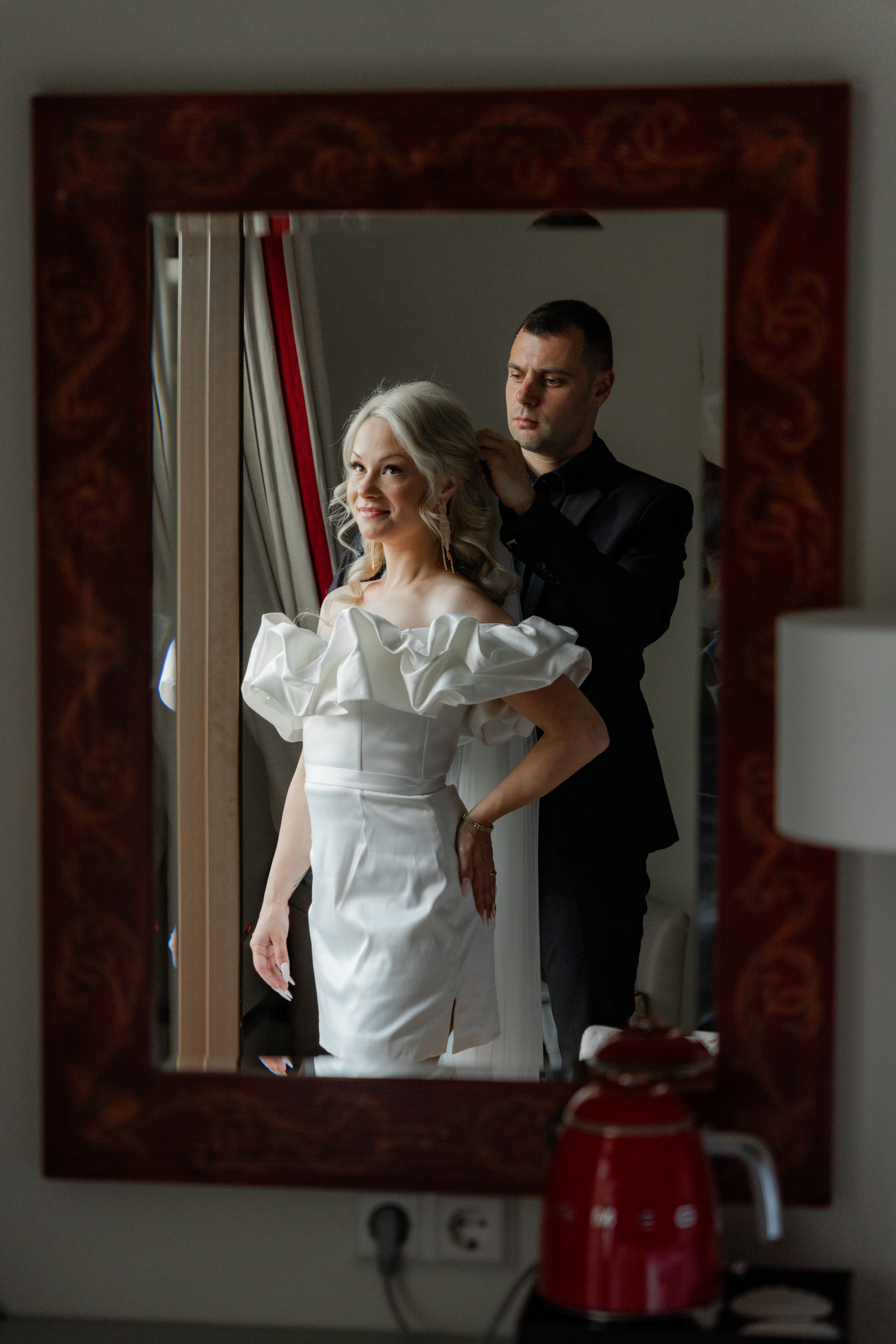 Жених одевает фату своей невесте в отражении в зеркале