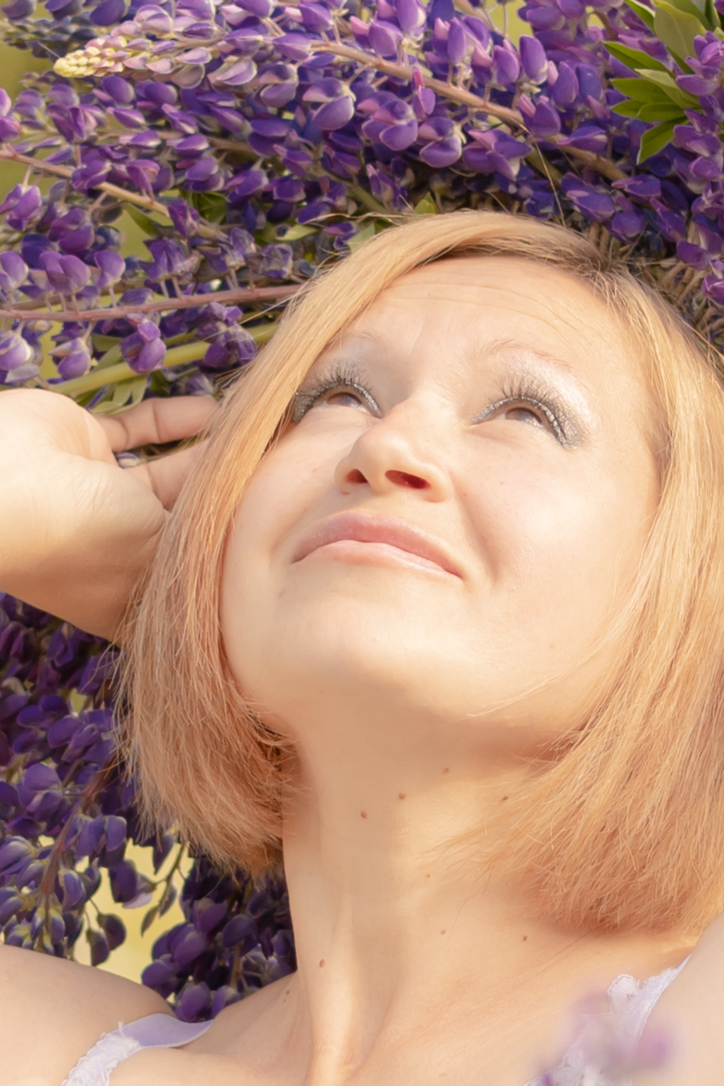 Женщина смотрит в небо. на голове венок из  люпинов