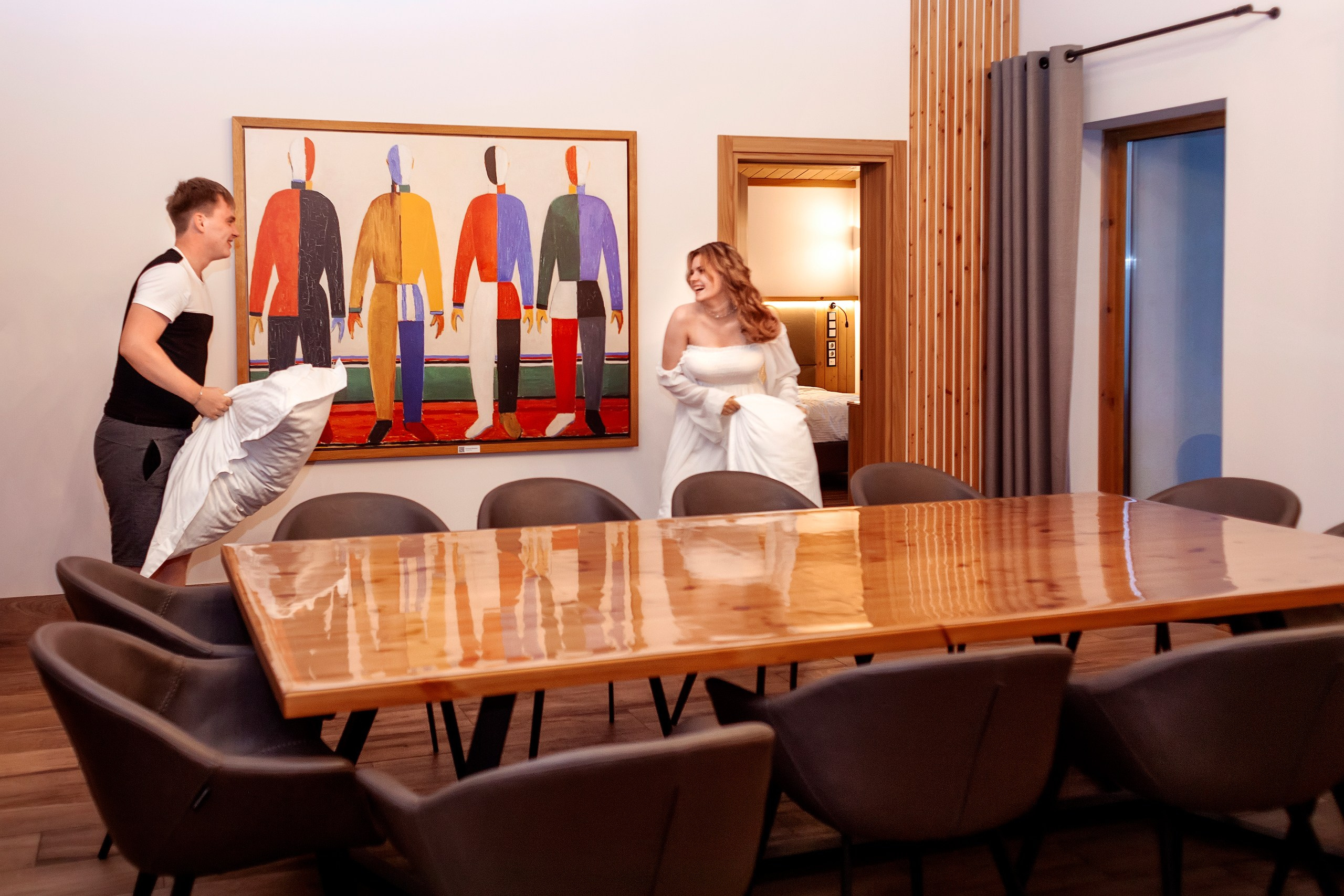 Парень с девушкой дерутся подушками внутри комнаты