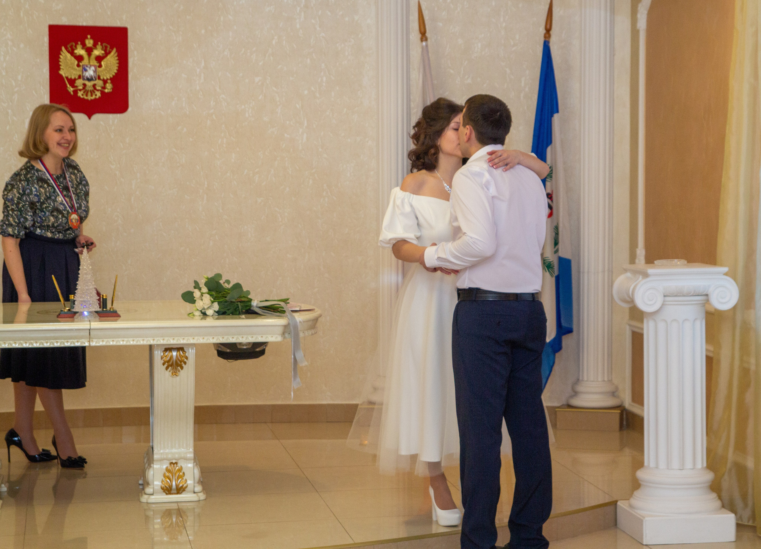 Молодожёны обнимаются и целуются после регистрации — кадр с эмоциями любви.