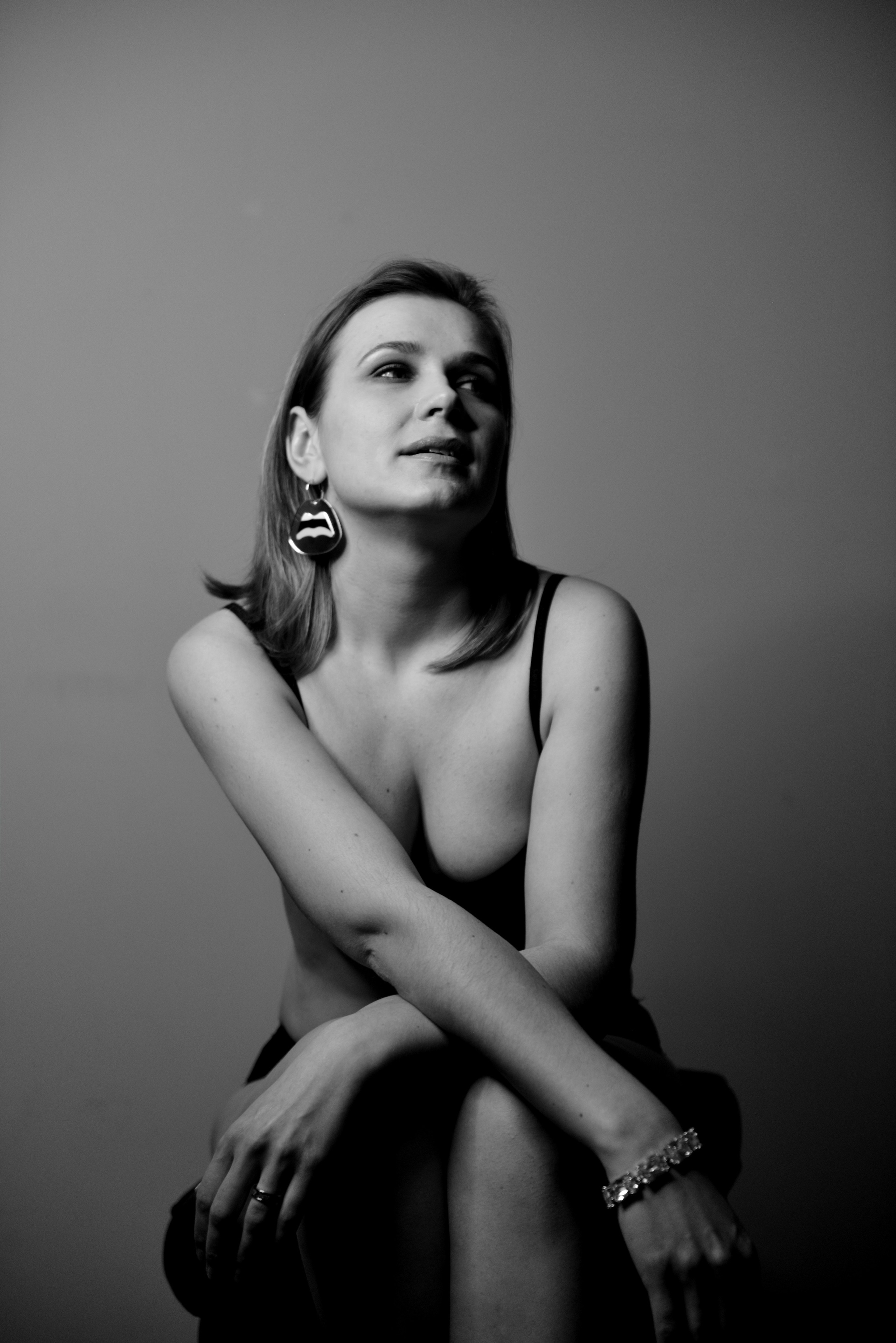 Красивая задумчивая умная девушка позирует, сидя на стуле.