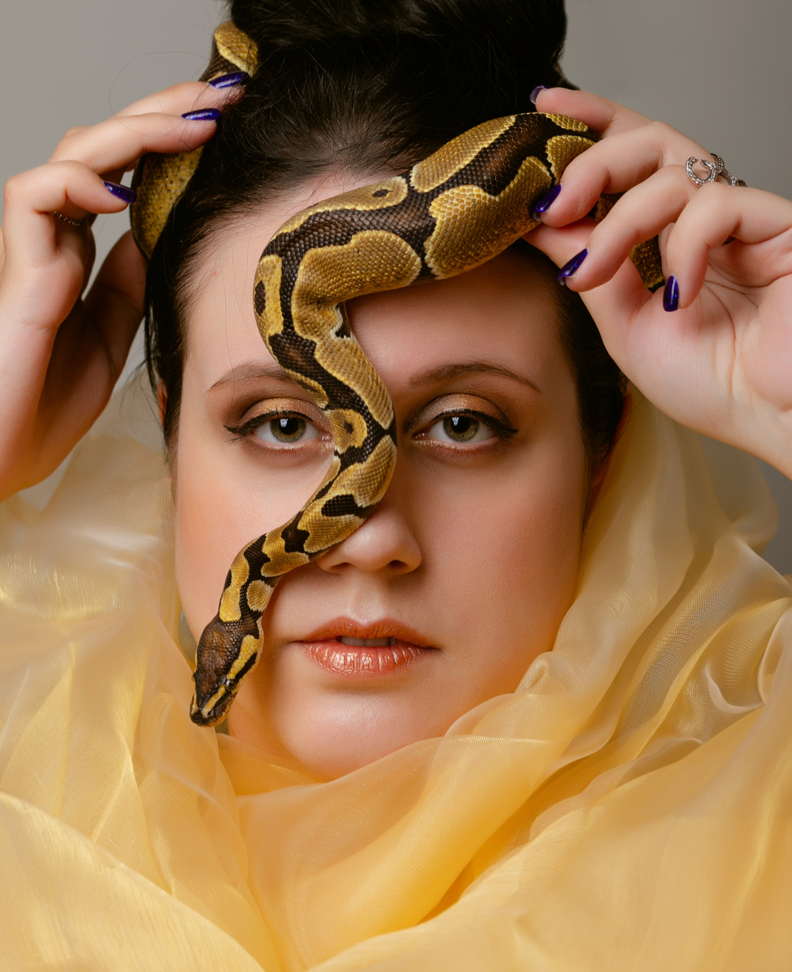 Девушка смотрит в кадр на её лице жёлтая змея