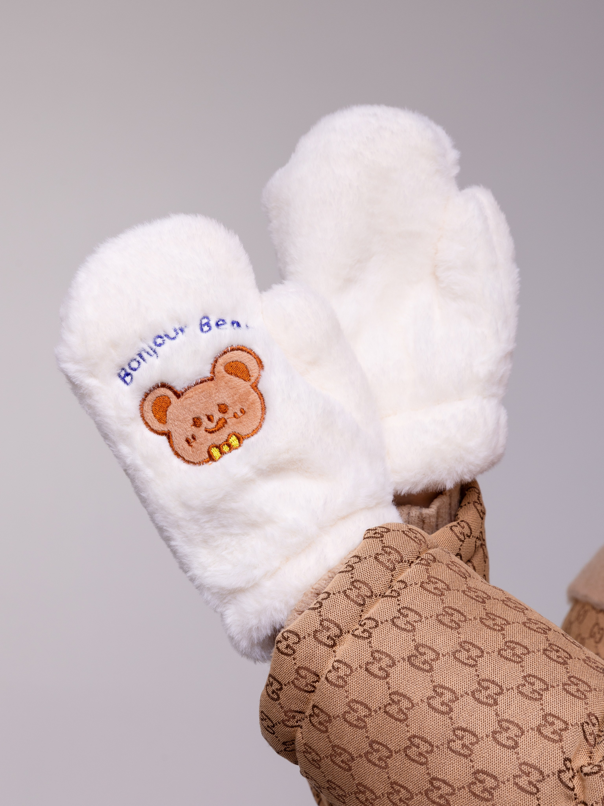 Белые варежки крупным планом с детскими аппликациями.