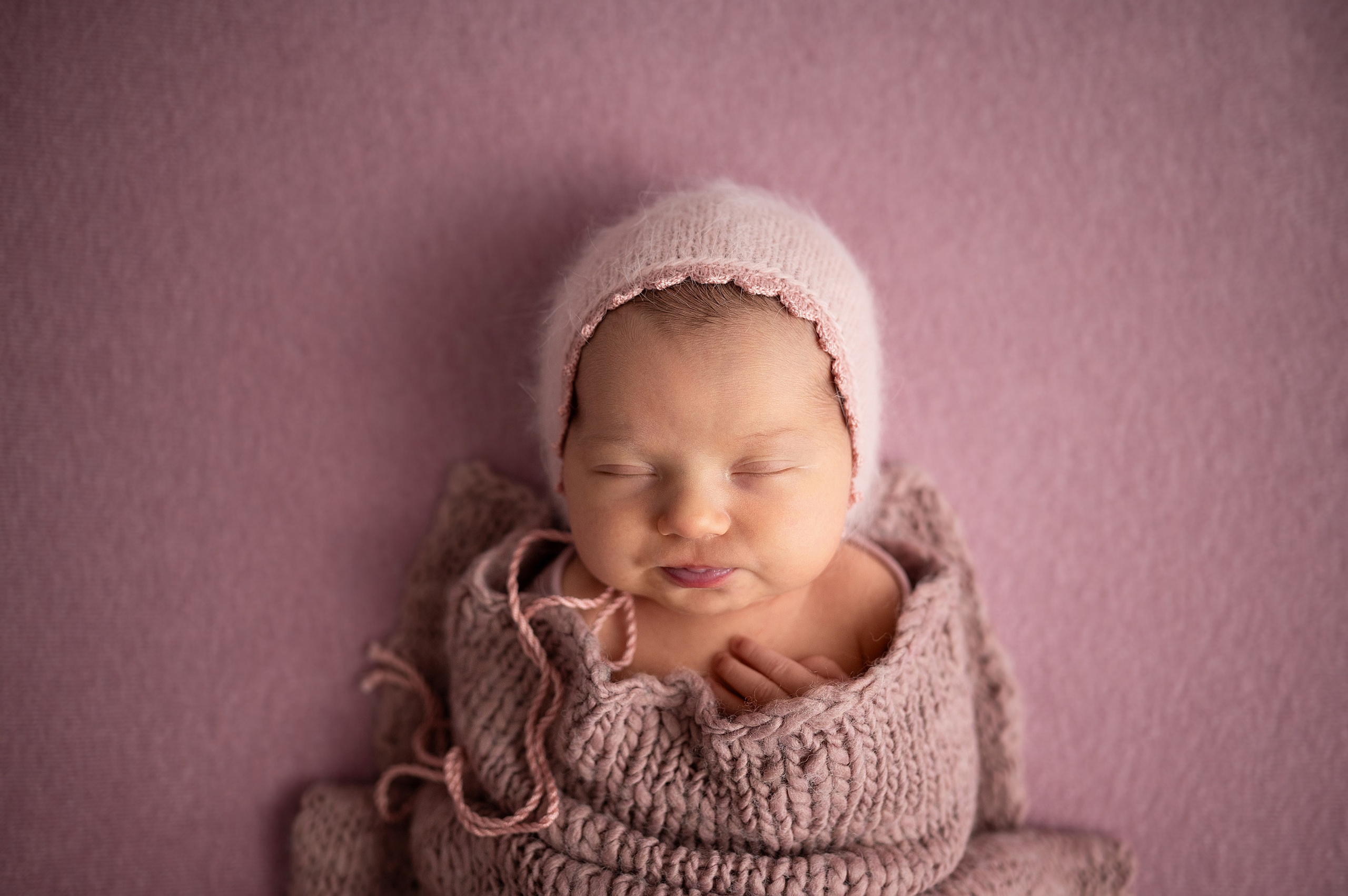 малышка в чепчике спит под одеялом на ньюборн фотосессия
