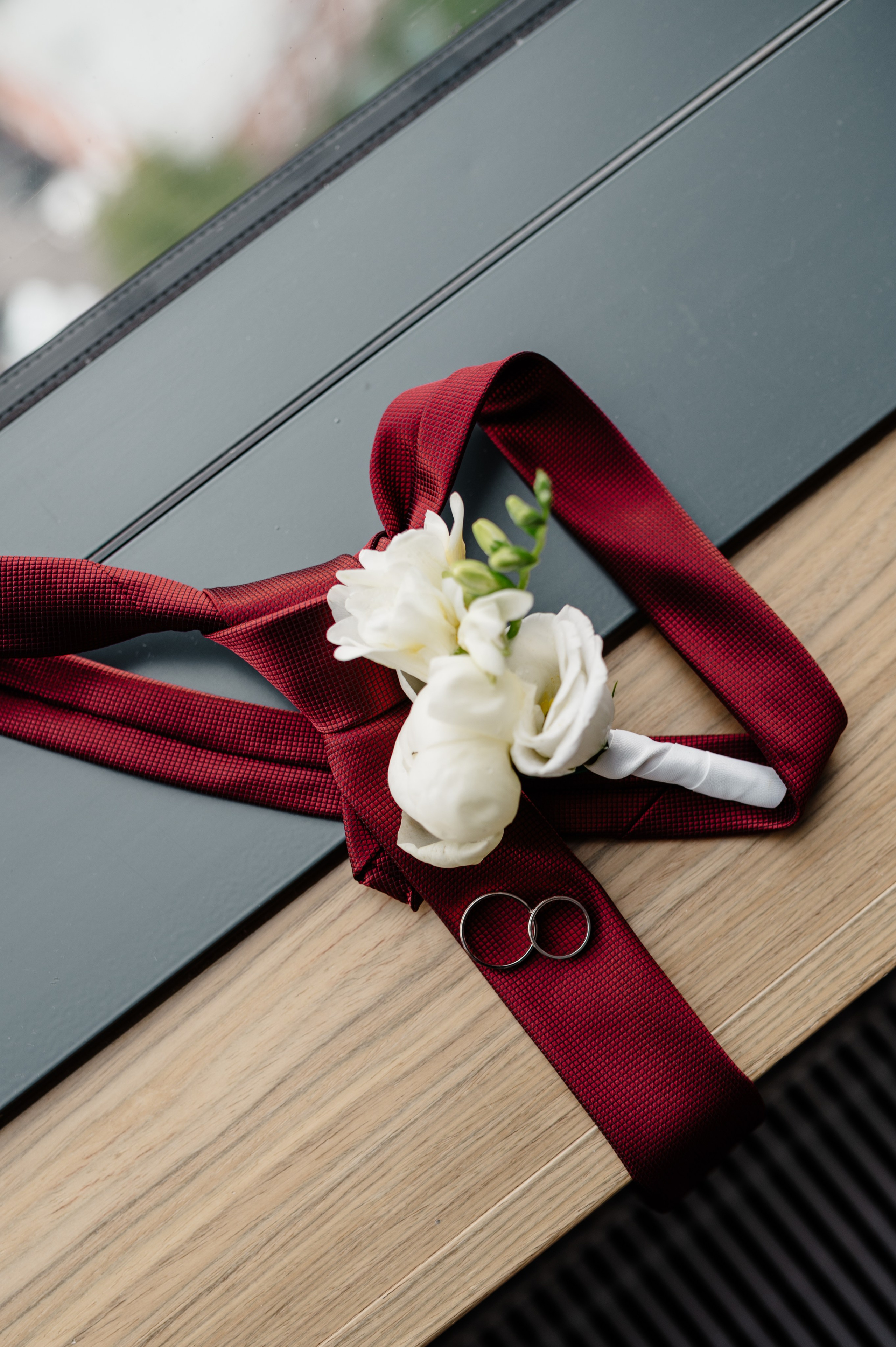 Бутоньерка с красным галстуком лежит на подоконнике.