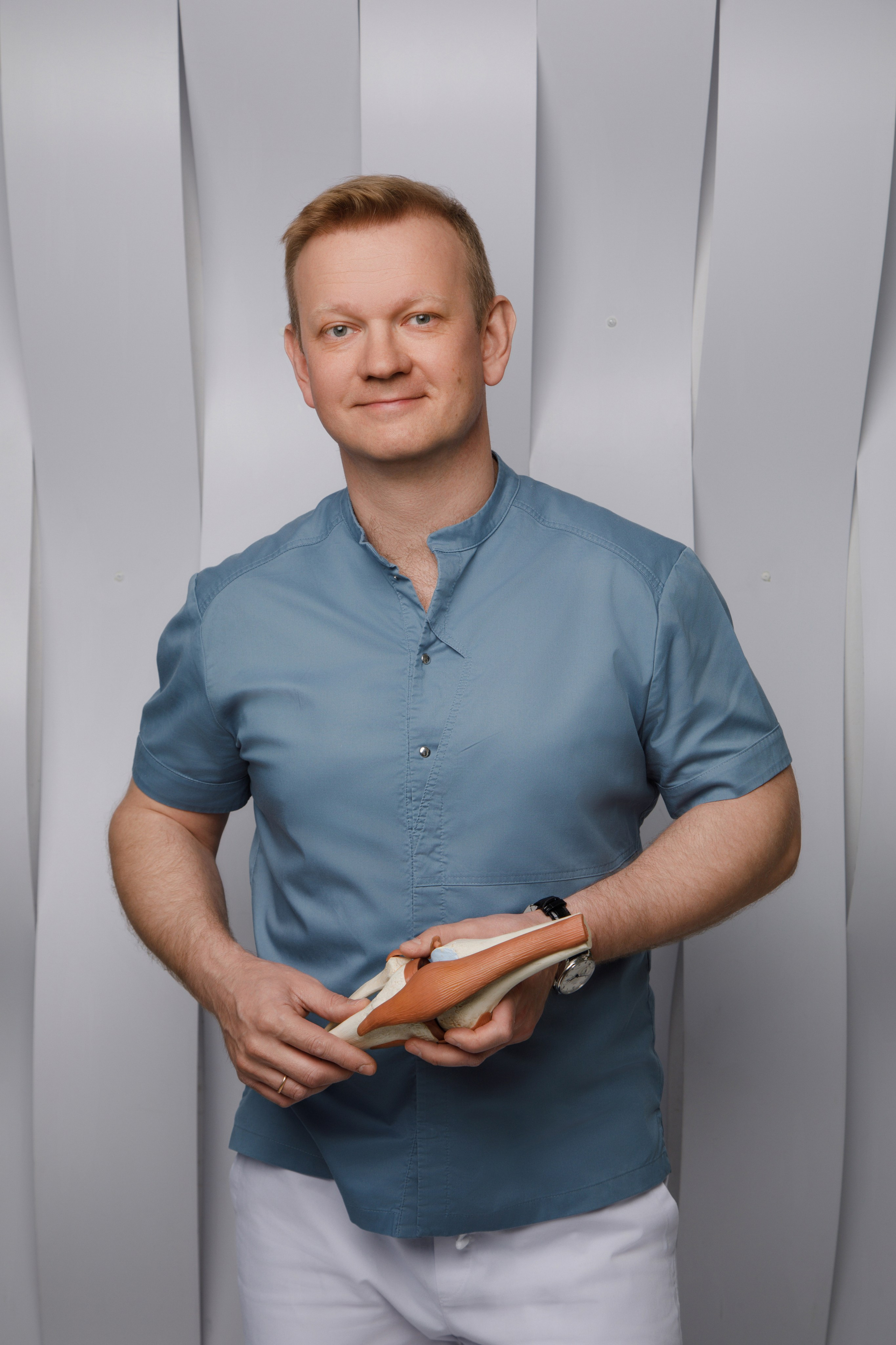 Профессиональный портрет мужчины-врача в белом халате на однотонном фоне.