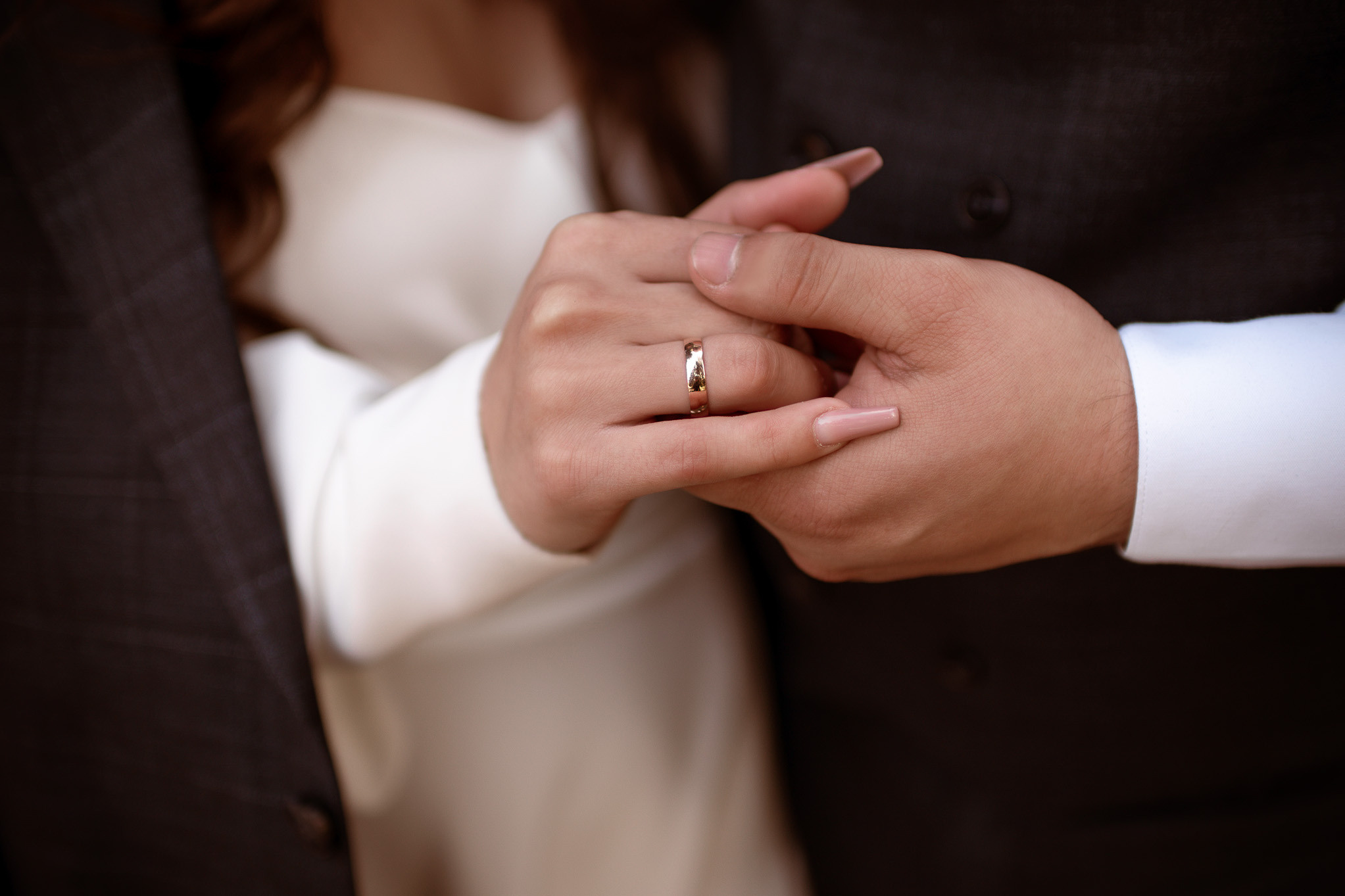 Жених держит за руку невесту, на руке невесты обручальное кольцо.