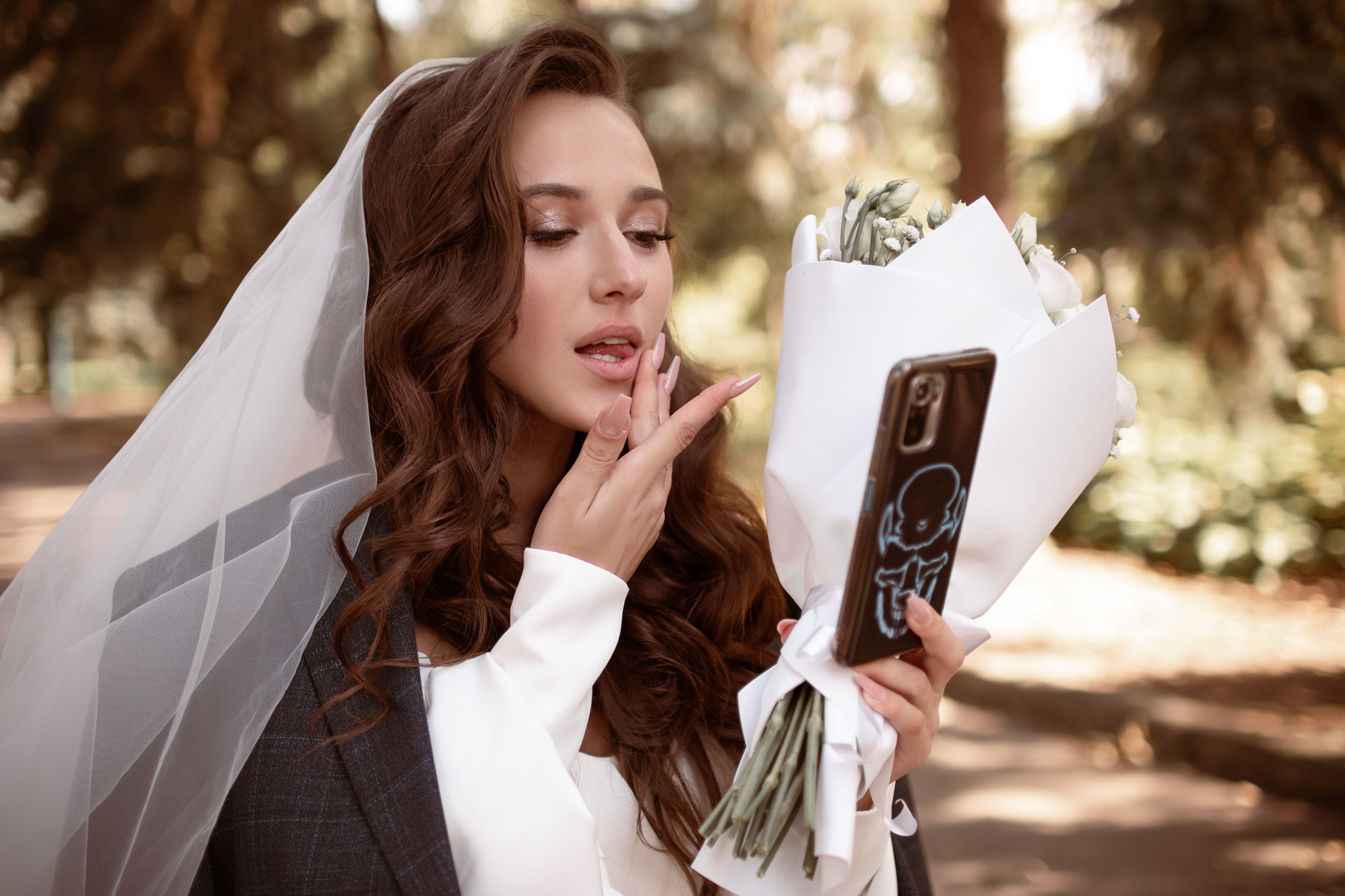 Невеста подкрашивает губы и смотрится в телефон.