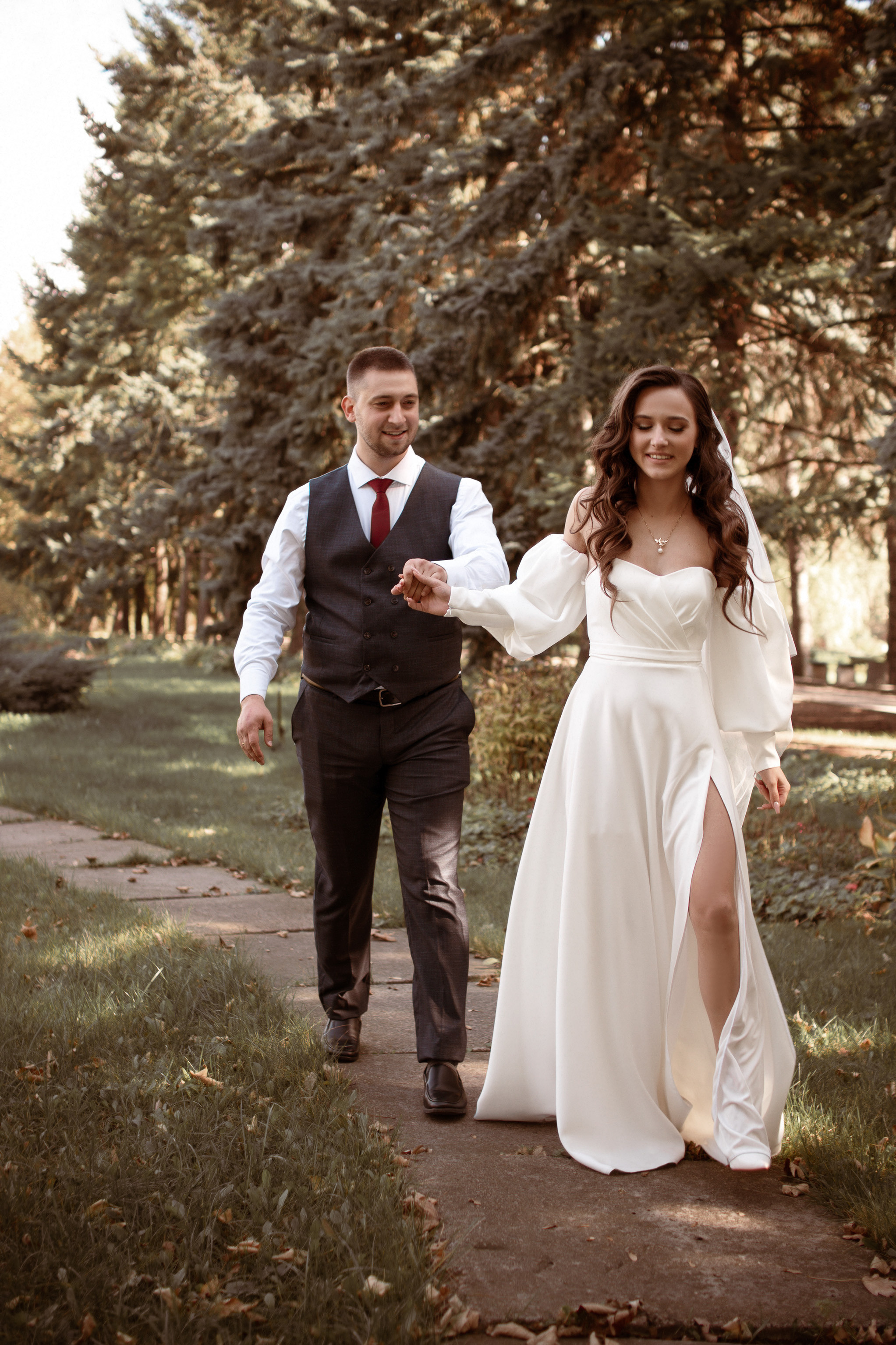 Жених с невестой в красивых нарядах идут держась за руку.