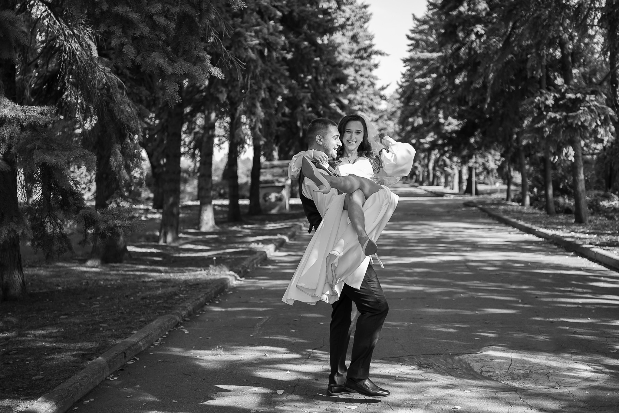 Жених кружит невесту на руках, пара прогуливается в парке.