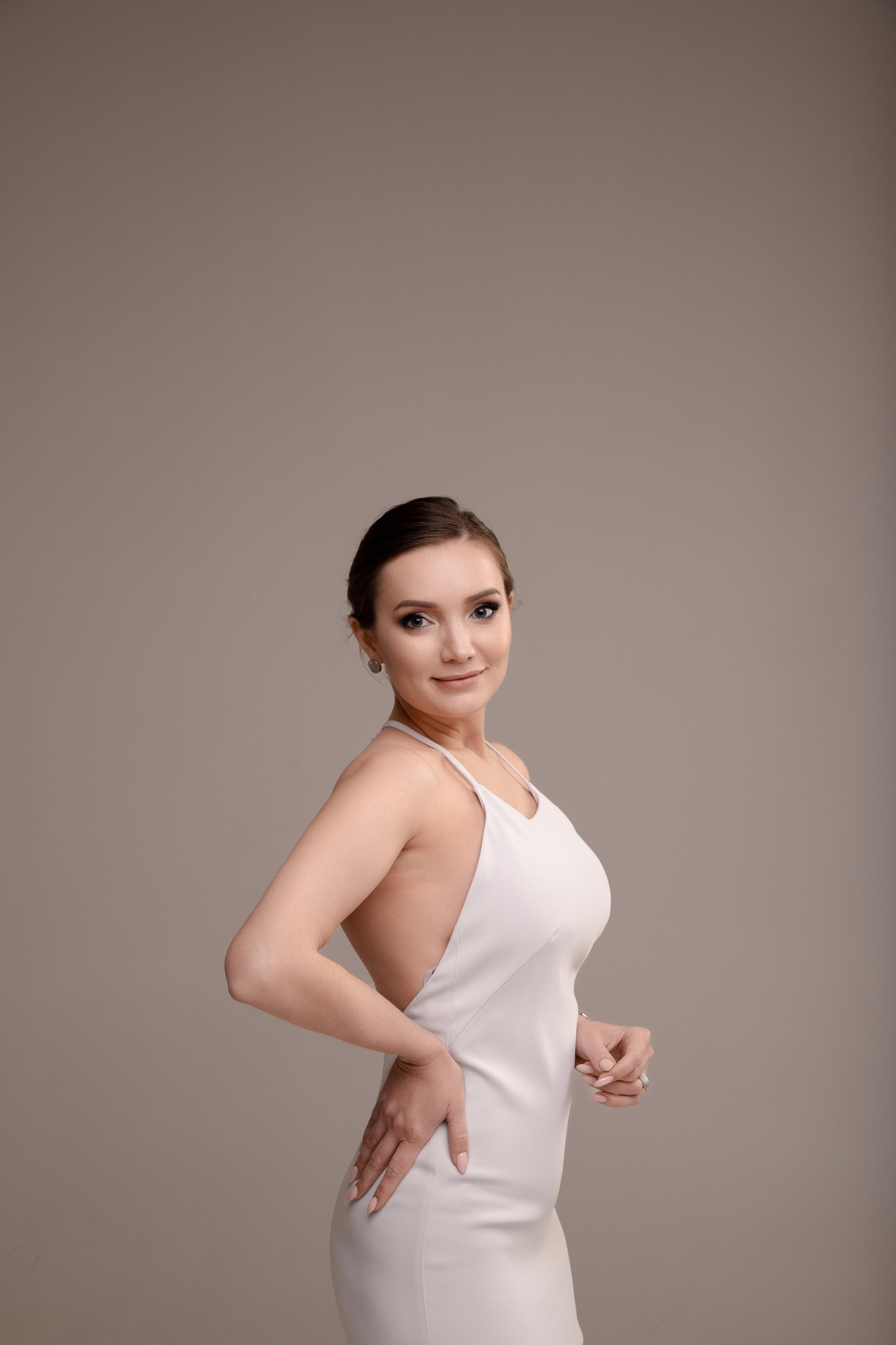 Студийный портрет девушки в шелковом белом платье комбинации на циклораме в теплой гамме