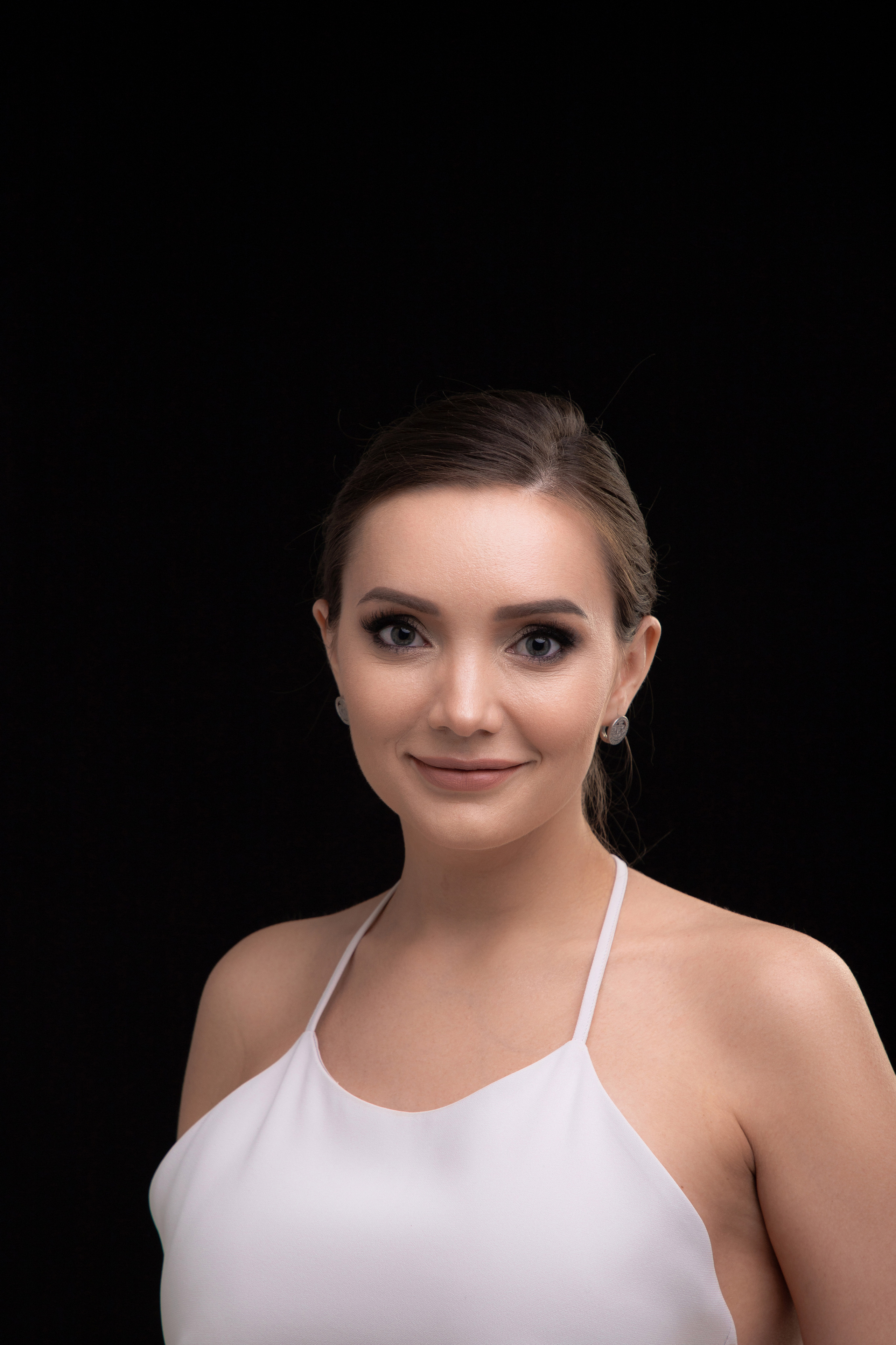 Студийная фотография портрета девушки на черном фоне в шелковом белом платье комбинации