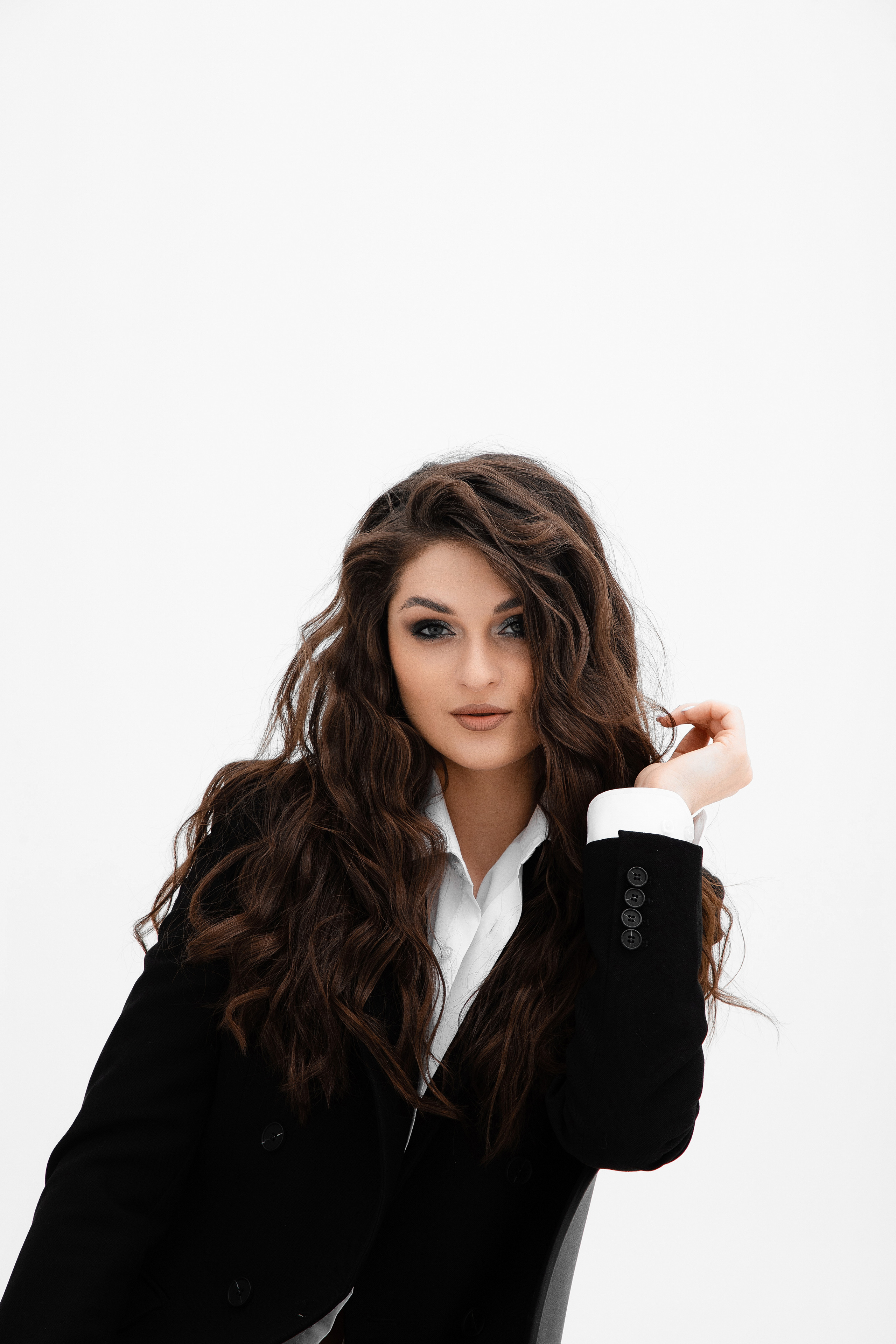 Портрет девушки в мужской рубашке и пиджаке на голое тело которая сидит на стуле