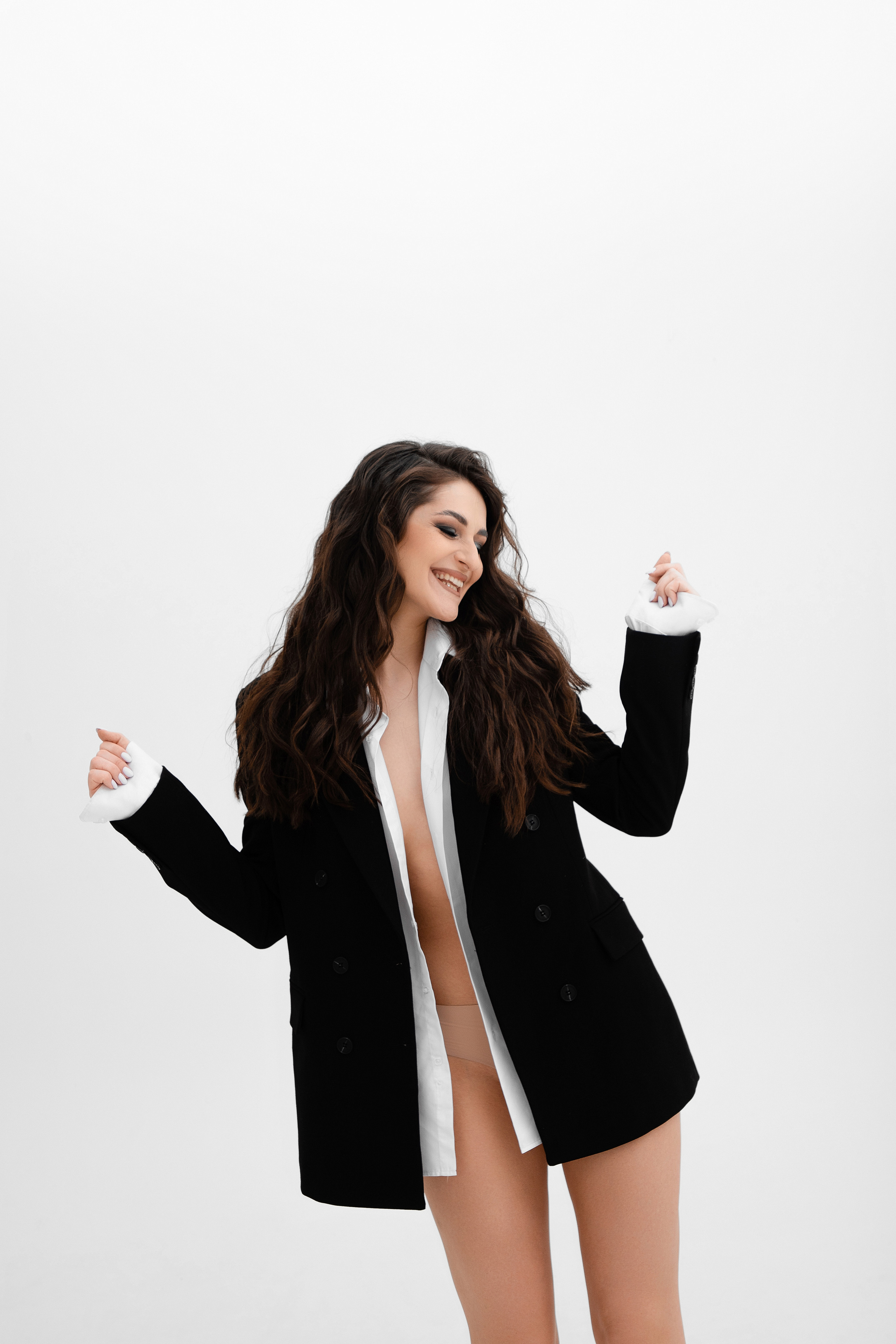 Портрет девушки в мужской рубашке и пиджаке на белом фоне на циклораме