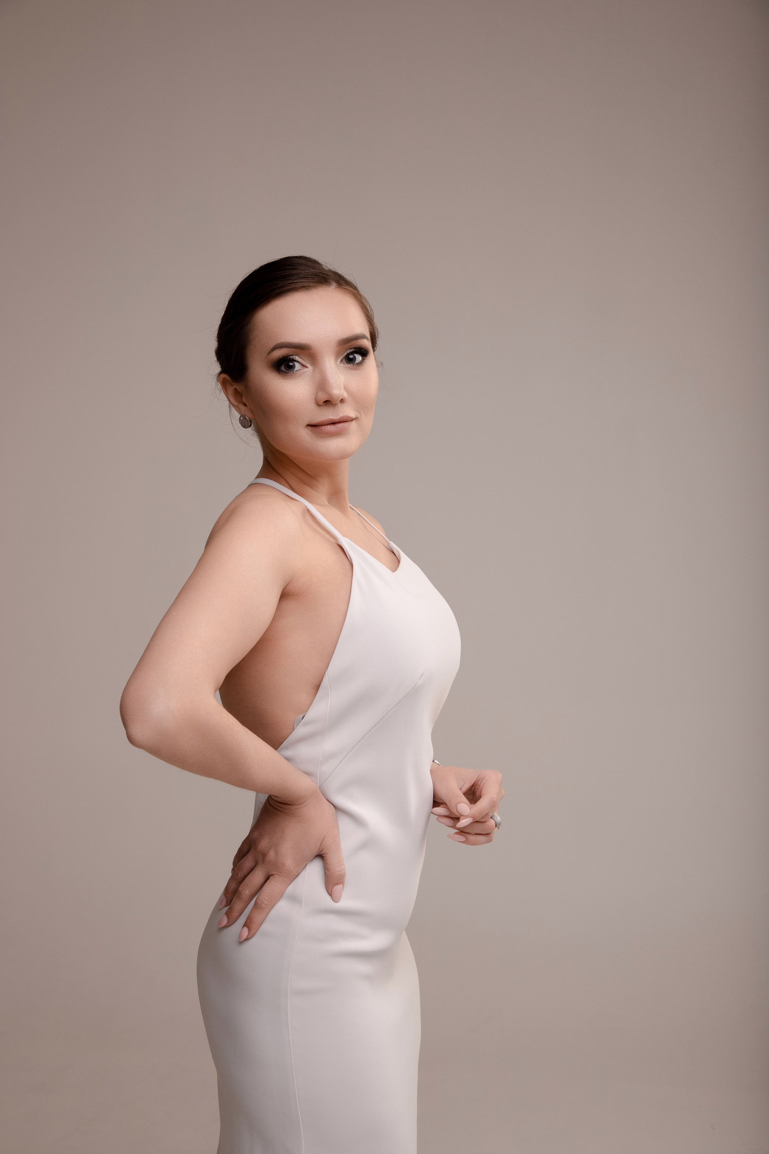 Студийный портрет девушки в шелковом белом платье комбинации на циклораме в теплой гамме