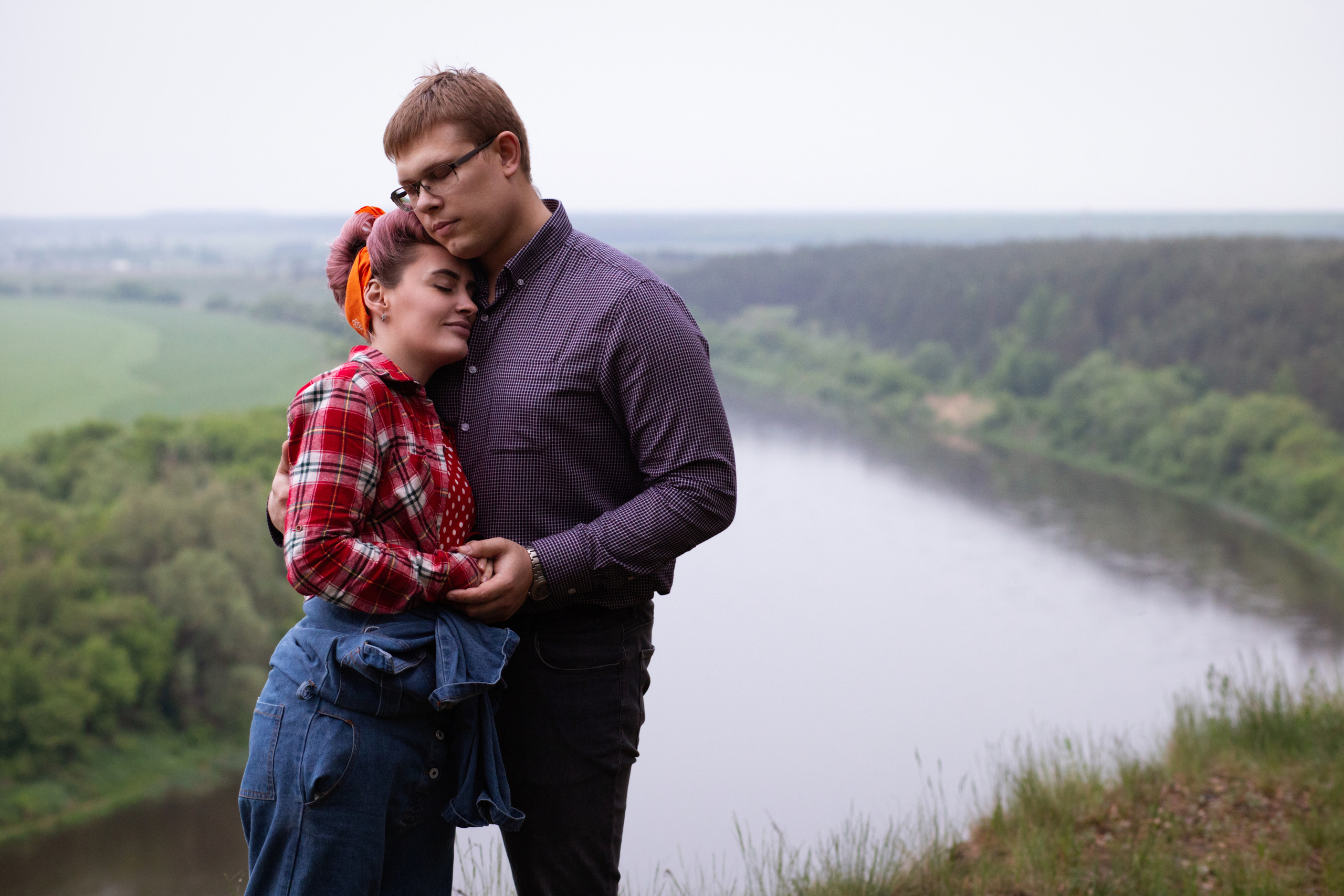 девушка  в ретро одежде обнимает молодого человека. они  стоят на  берегу    извилистой  реки.
