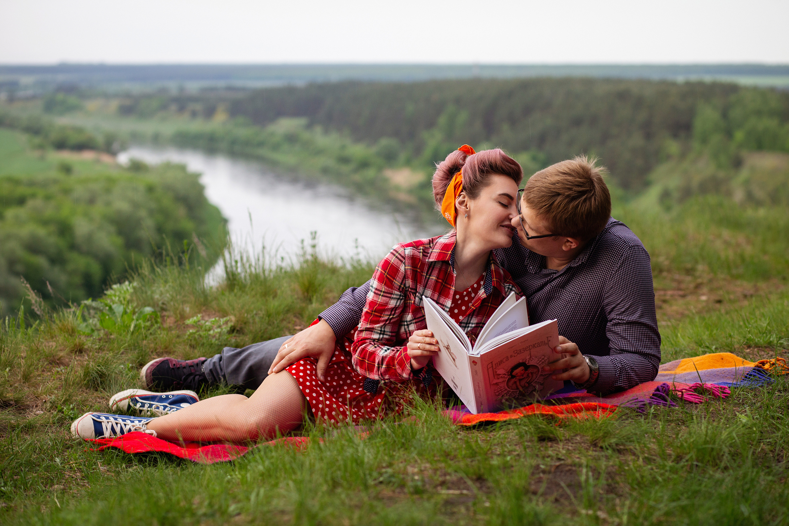 девушка  в  красной  ретро одежду  и  головном уборе    целует молодого  человека. На фоне    извилистая река.
