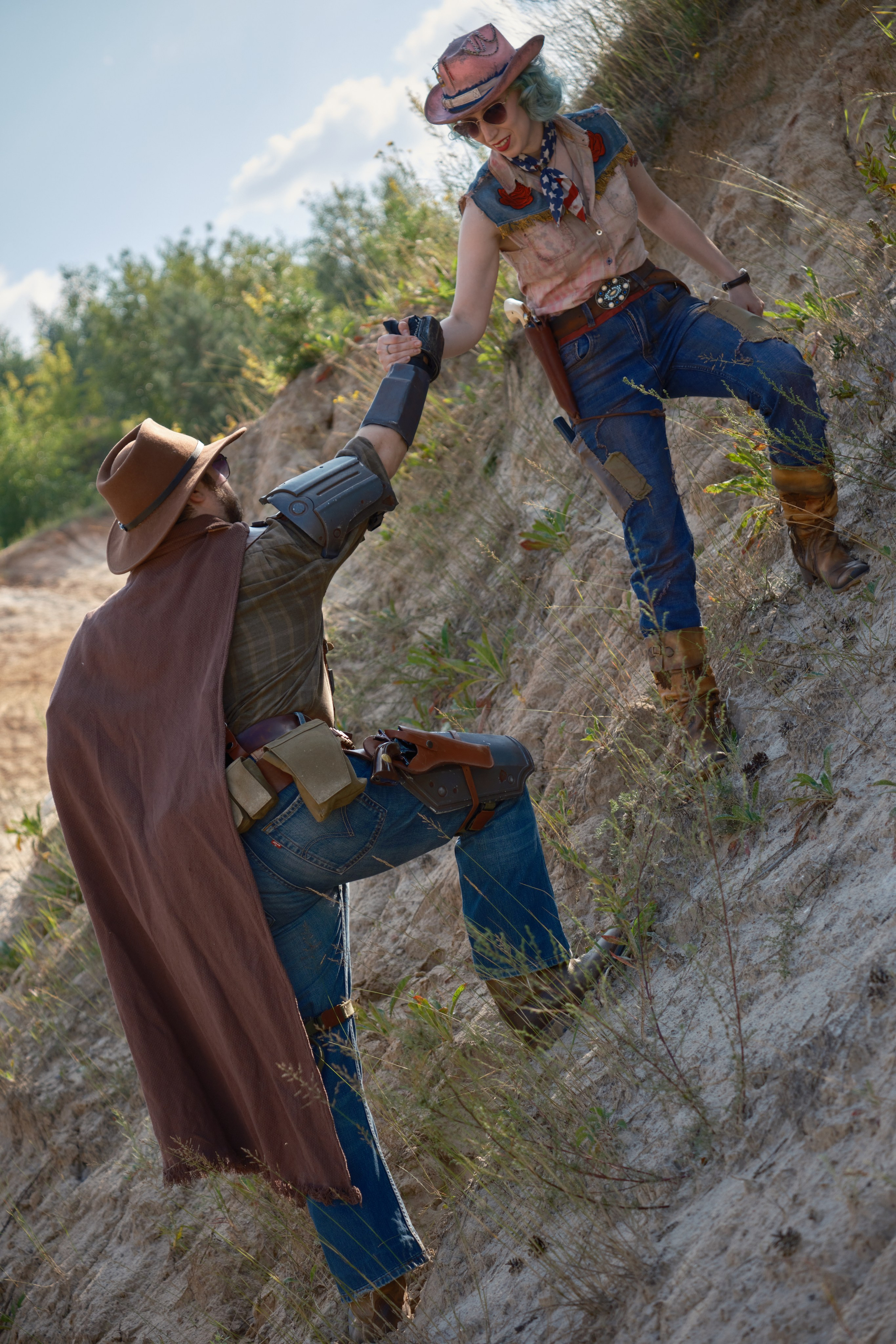Мужчина и девушка в ковбойских шляпах поднимаются на гору