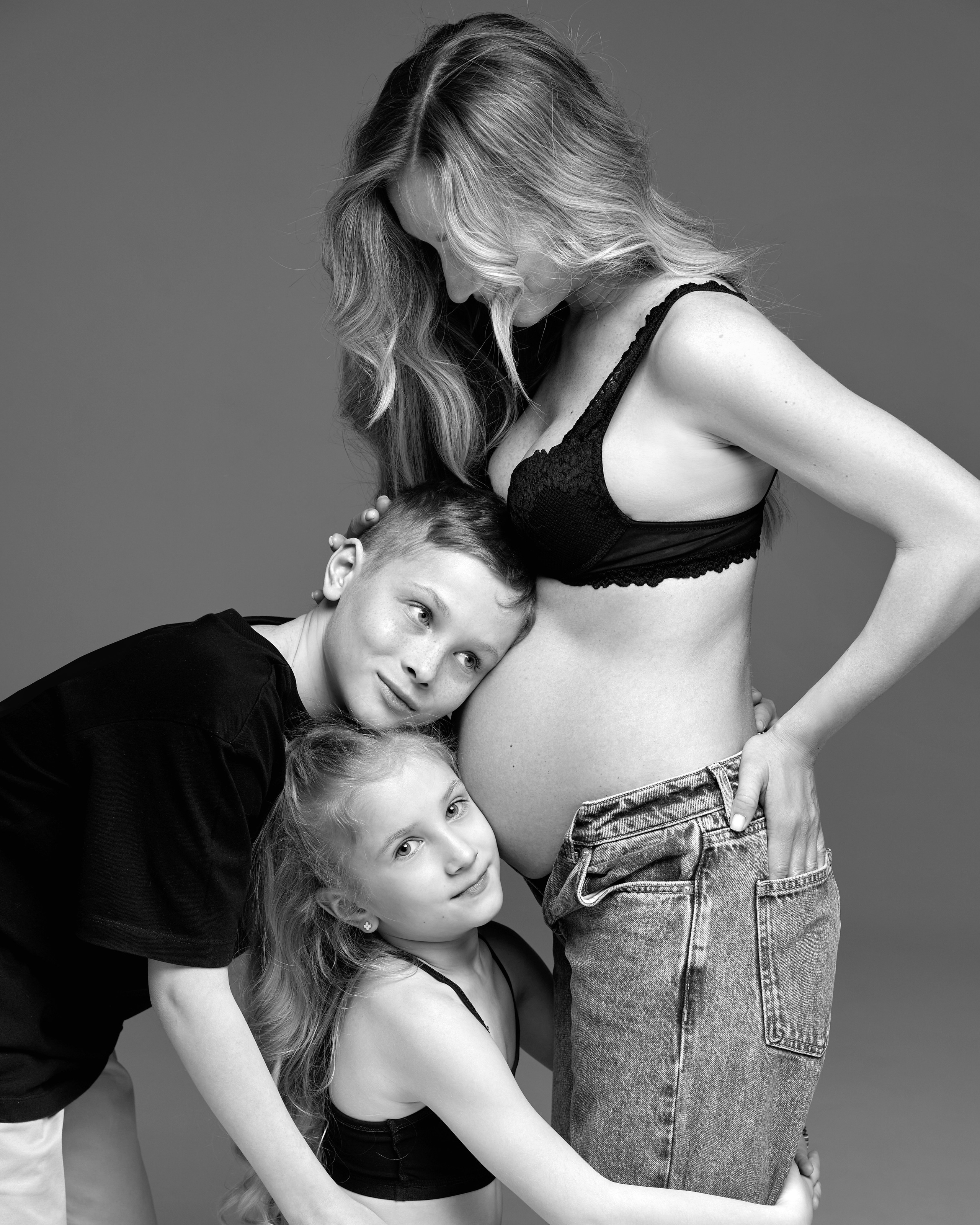 еплая семейная сцена: беременная женщина с сыном и дочкой. Дети нежно прижимаются к животу мамы — ожидание нового члена семьи