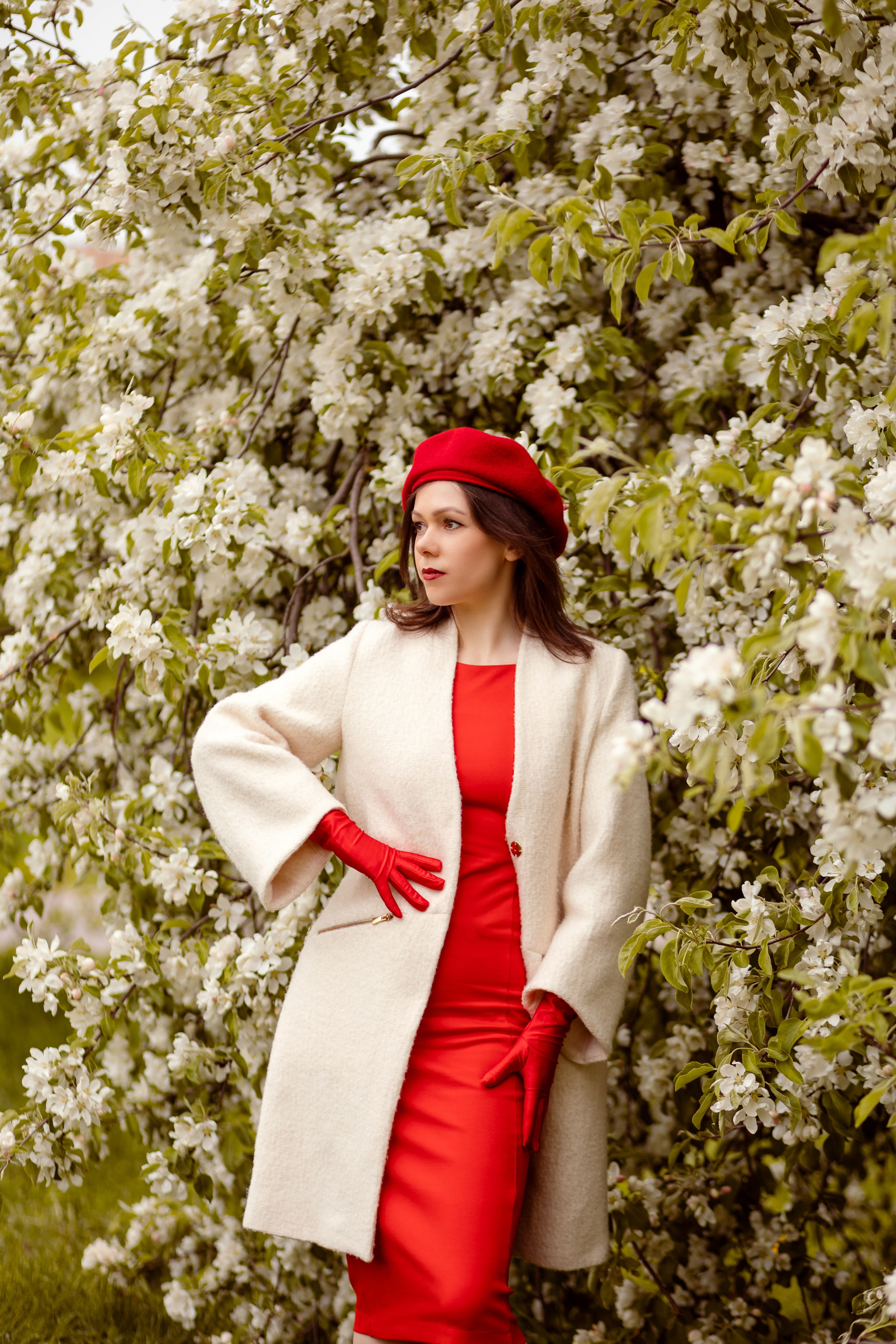 Стильно одетая дама среди цветущих яблонь