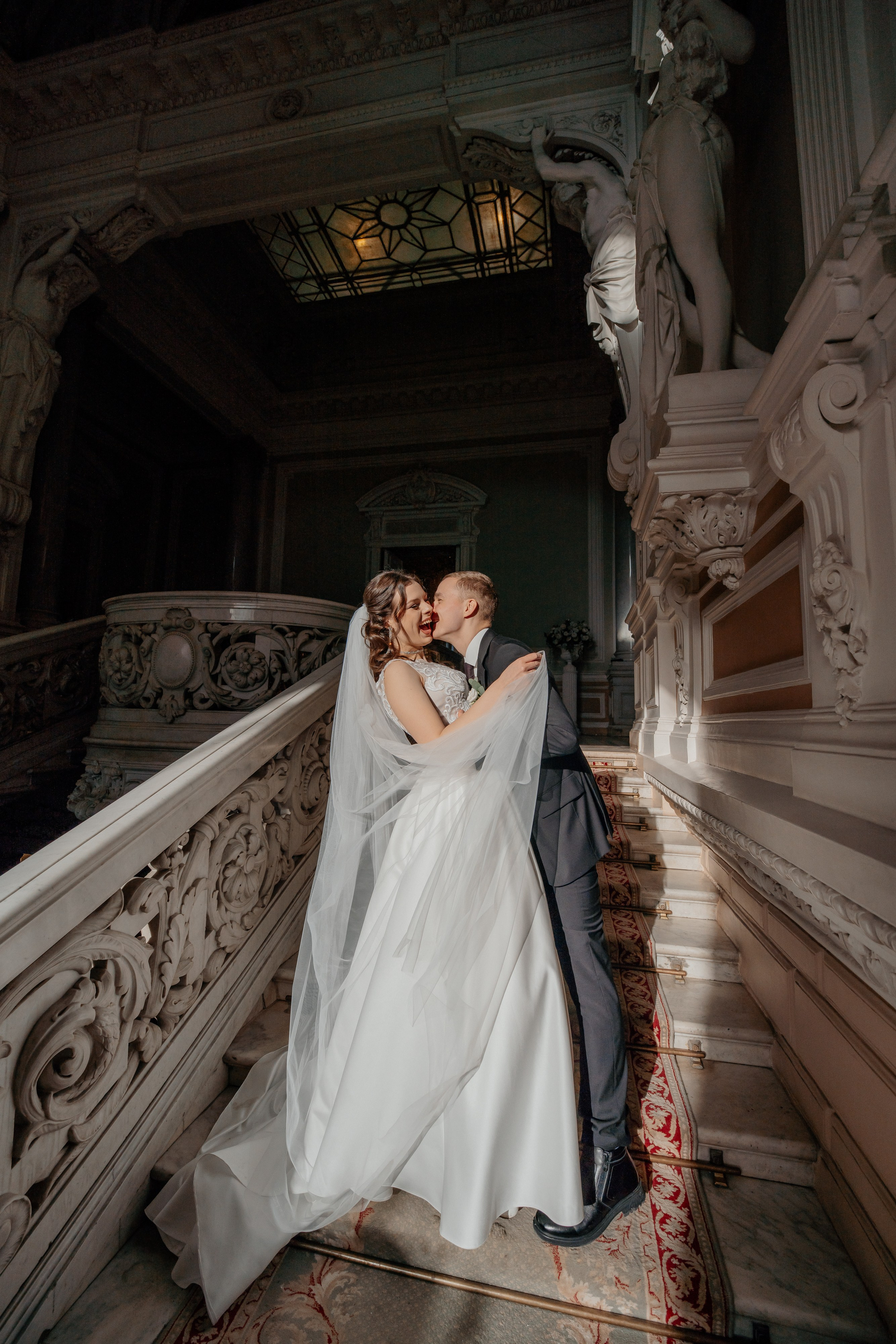 Свадебная фотосессия в Санкт-Петербурге во дворце  бракосочетания №1 на Английской набережной. Невеста и жених стоят на освещенной солнцем лестнице в лучах света.
