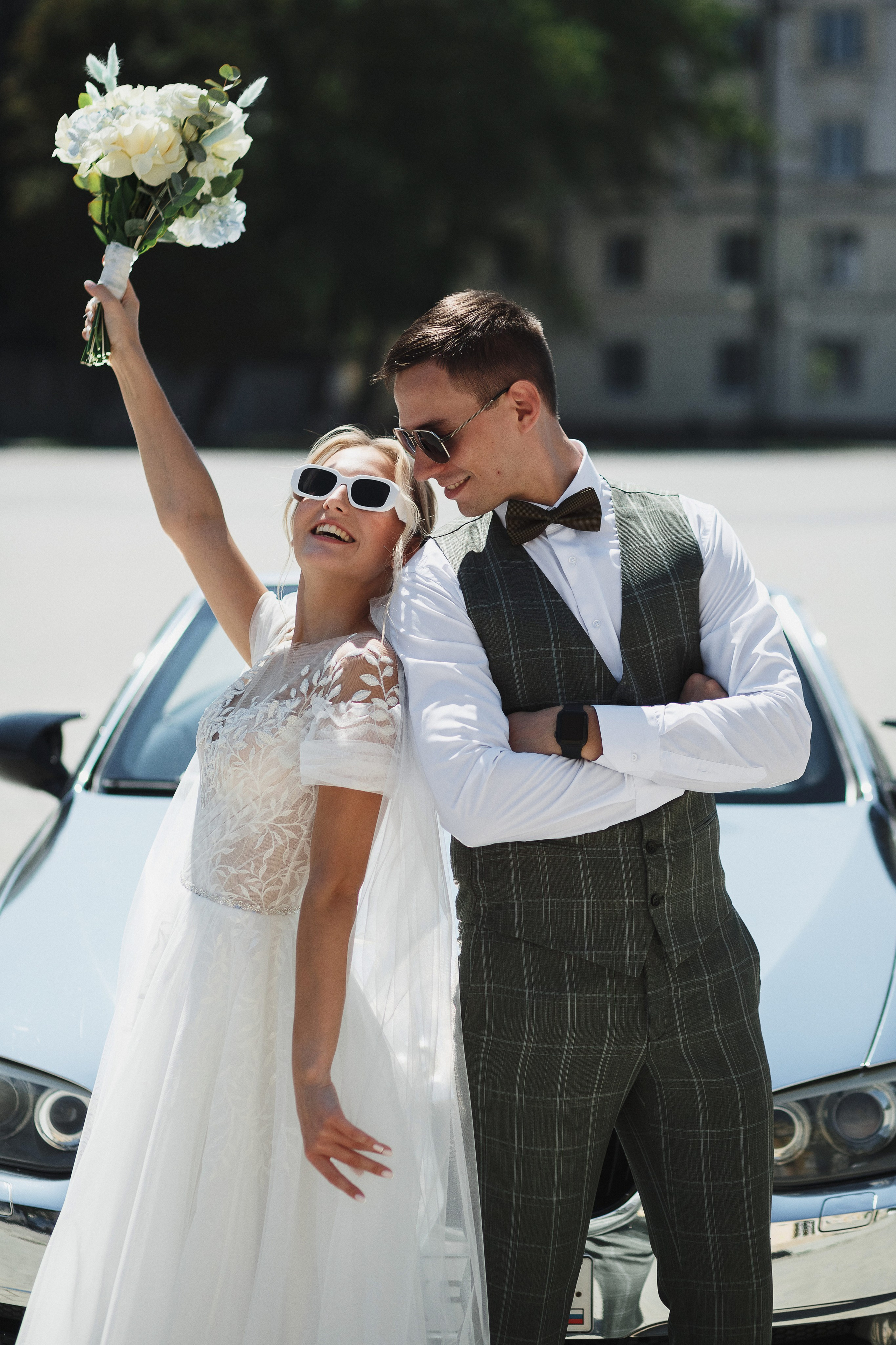 Свадебная прогулка в Таганроге: Веселые моменты на фоне элегантной машины. Романтическая атмосфера и незабываемые впечатления в день свадьбы.