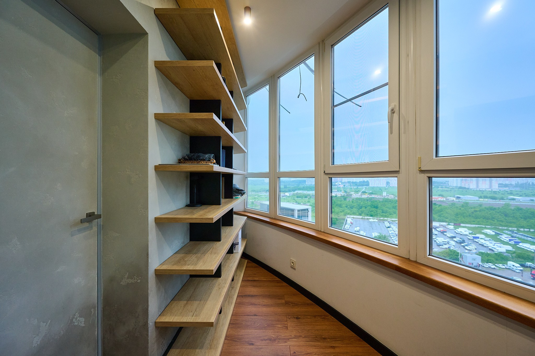 балкон с видом на улицу деревянными подставками для вещей и мраморной серой дверью 