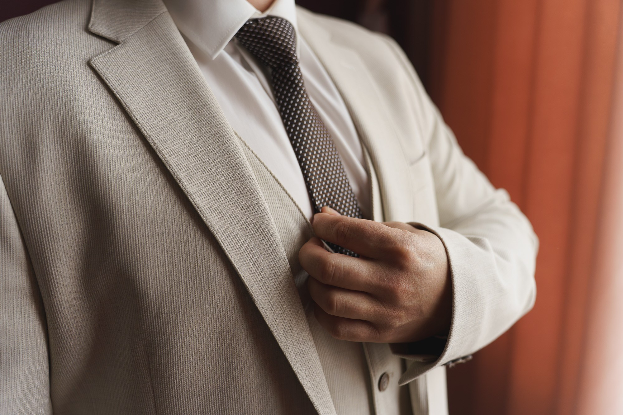 Жених в костюме аккуратно поправляет костюм — подготовка к церемонии. Фото от Свадебного фотографа в Екатеринбурге Евгения Карася