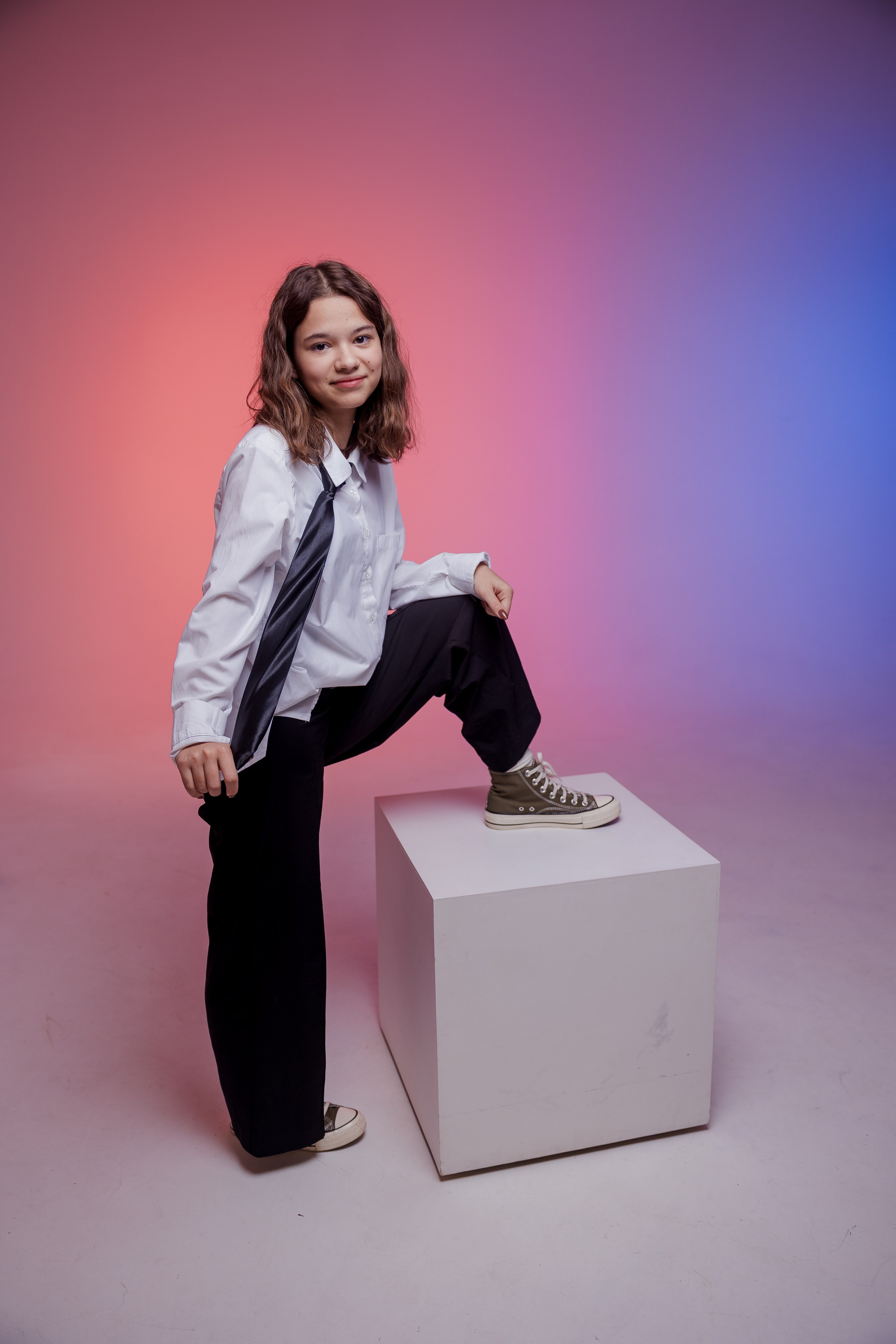 Девушка стоит в фотостудии с цветным светом