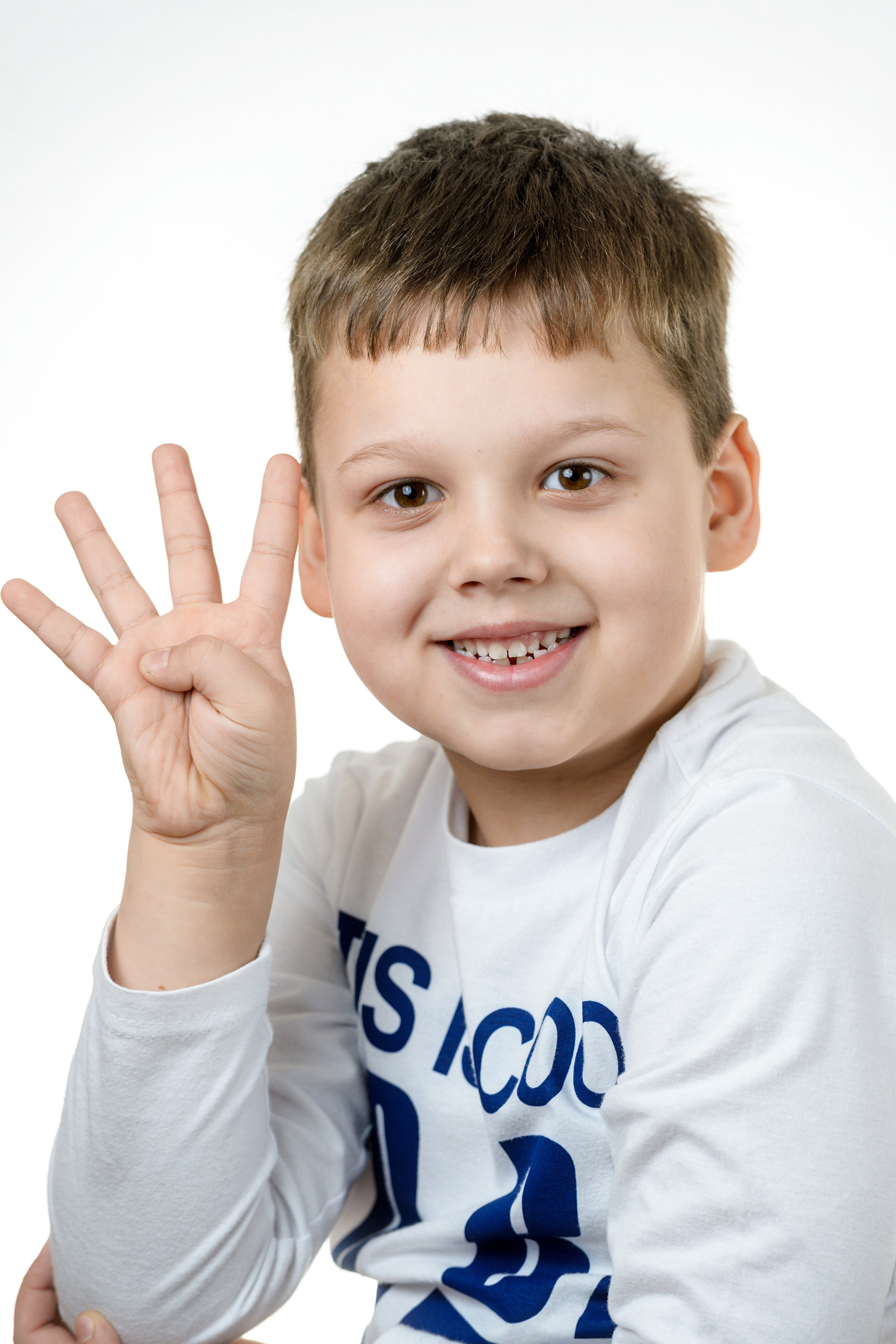 Мальчик в сером свитшоте показывает четыре пальца в студийном кадре на белом фоне.