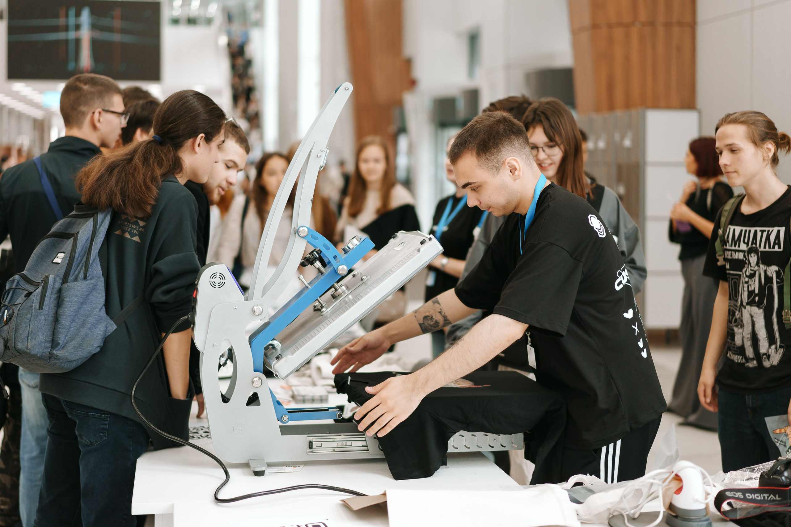 Посетители выставки наблюдают за печатью на футболке — стенд CustomLab Казань Экспо