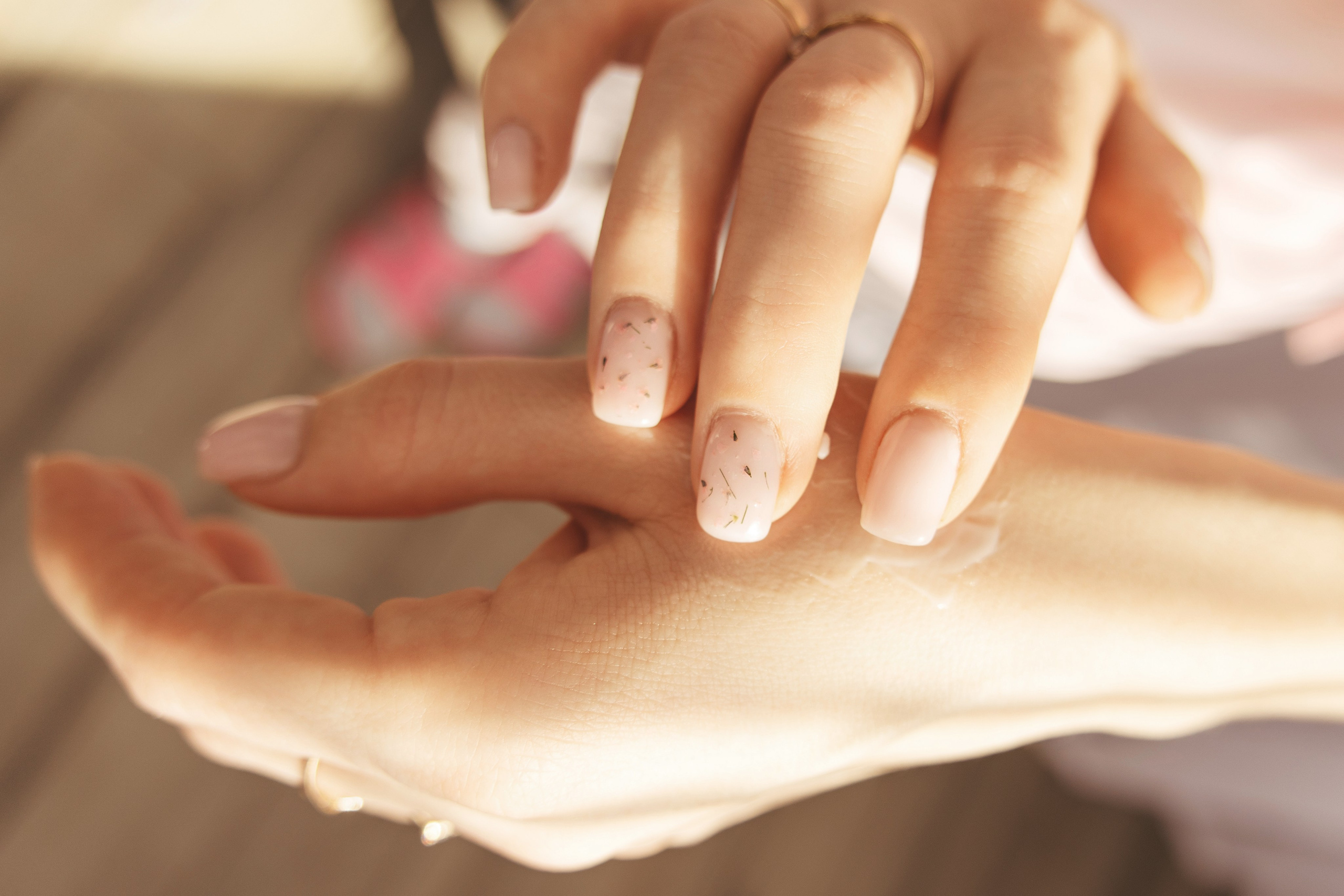 Косметолог - наносит крем на кисти рук, крупный план