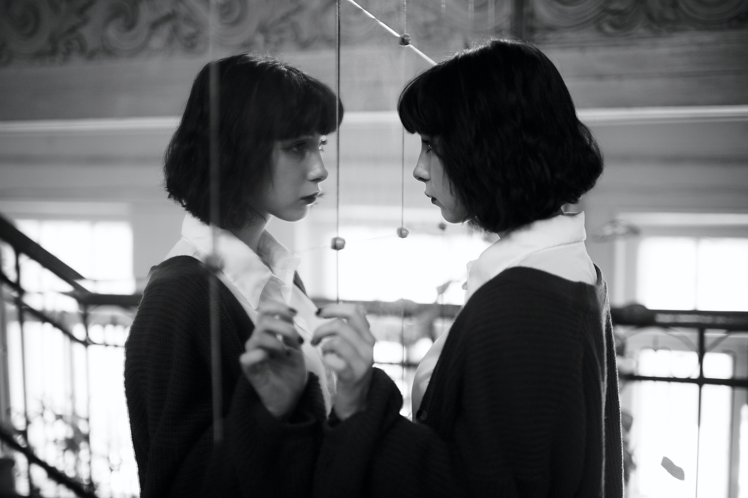 Девушка с каре смотрит на своё отражение в зеркале